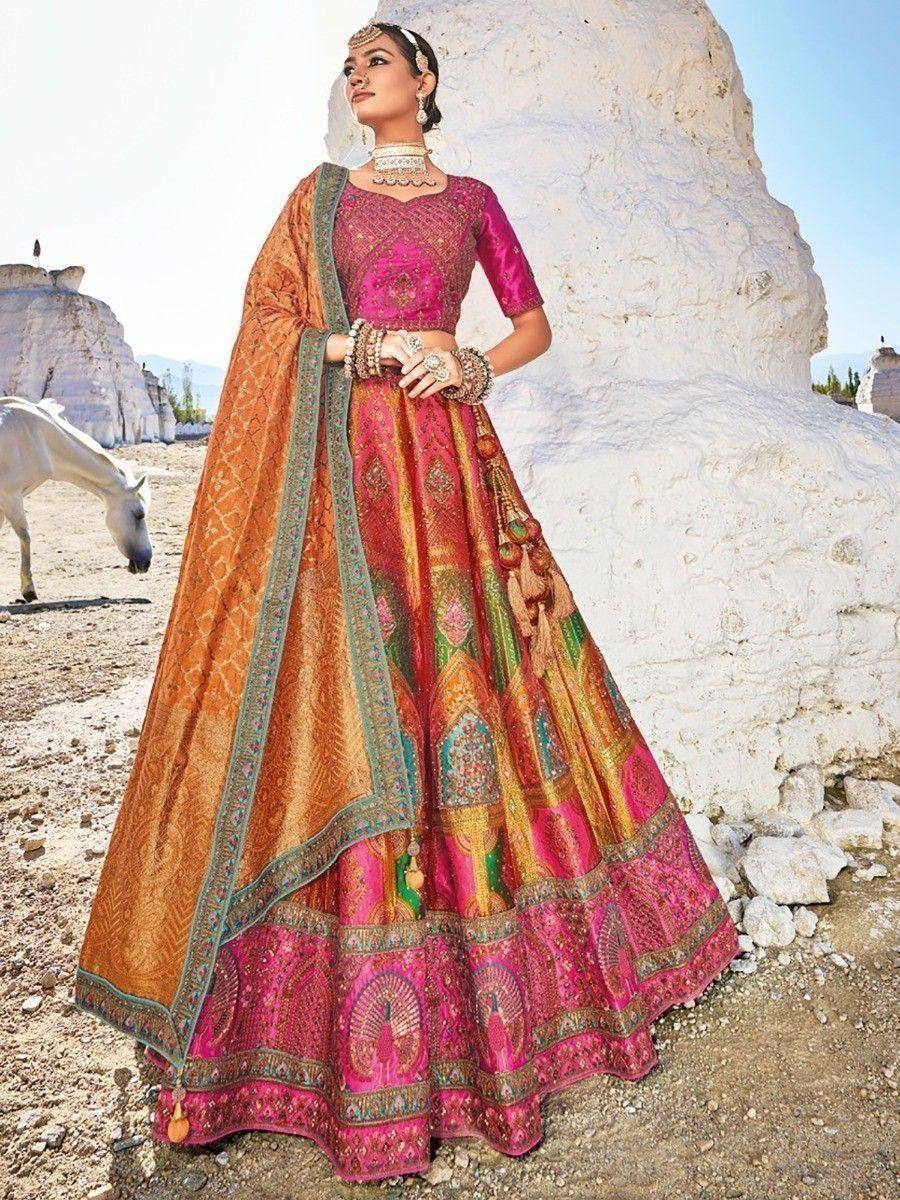 Vibrant pink and gold designer lehenga choli with intricate embroidery, paired with matching dupatta, perfect for Indian weddings.