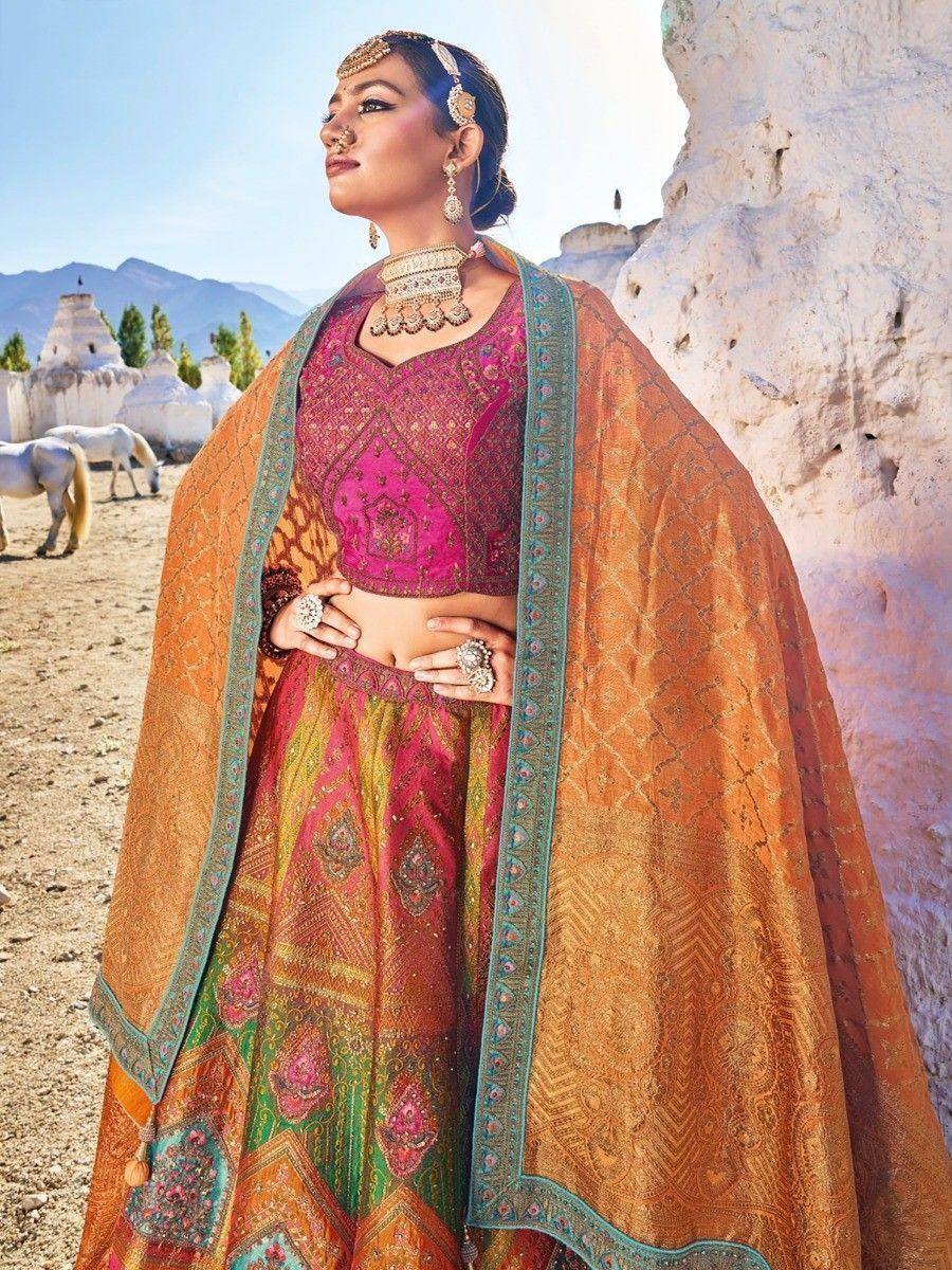 Woman in vibrant pink and orange designer lehenga choli with embroidered dupatta, traditional Indian ethnic wear