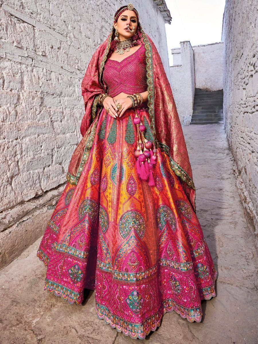 Vibrant pink and orange designer lehenga choli with intricate embroidery, perfect for Indian weddings and festive occasions.