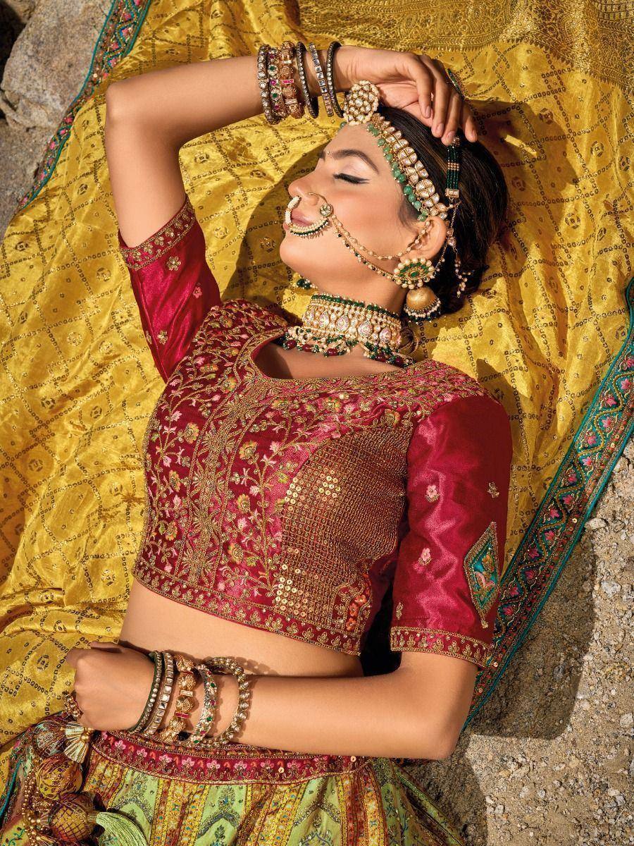 Woman in maroon embroidered lehenga choli with gold jewelry and yellow dupatta, ethnic Indian wear