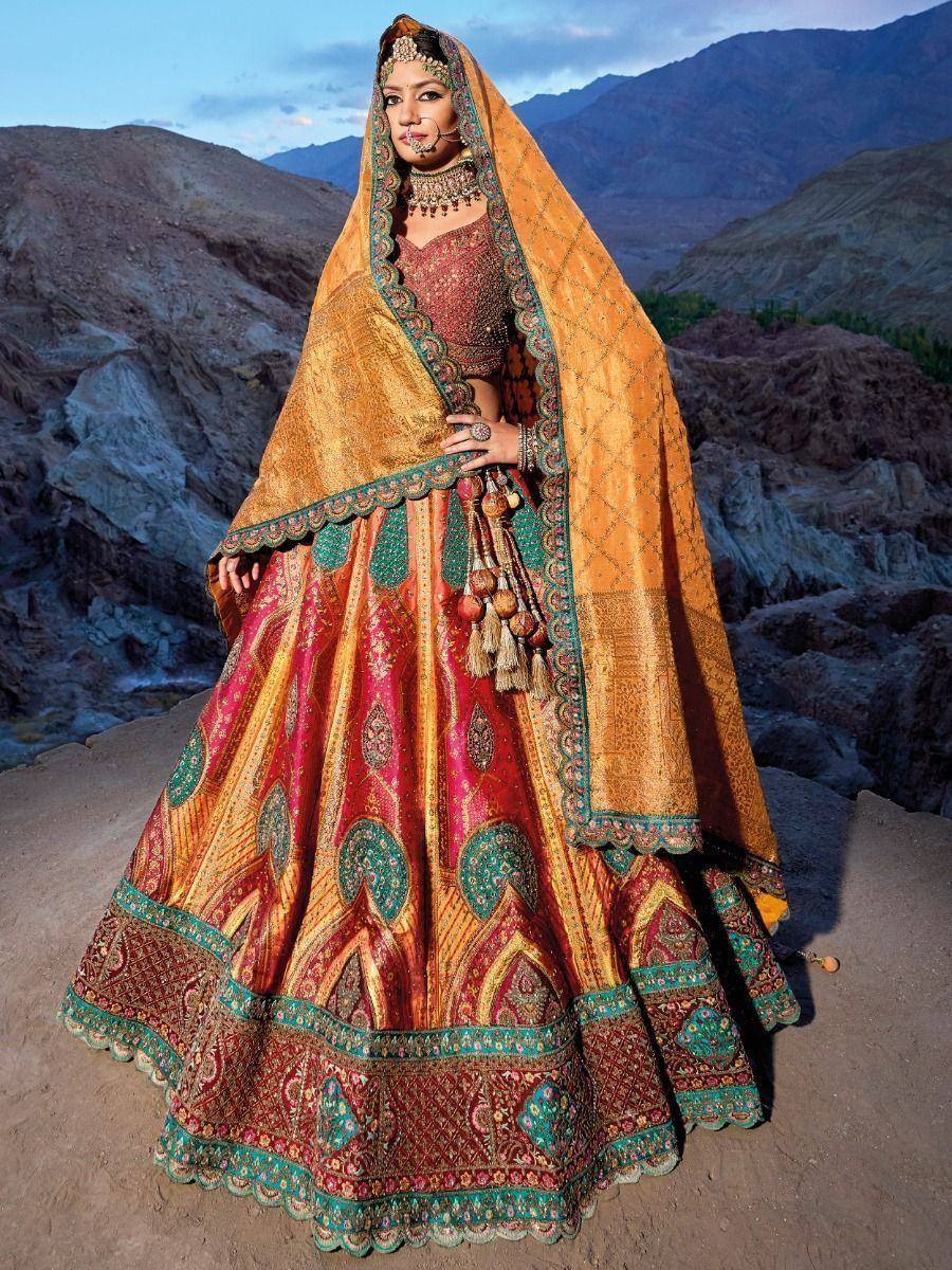 Indian bridal lehenga choli with intricate embroidery, gold dupatta, and traditional jewelry against mountain backdrop