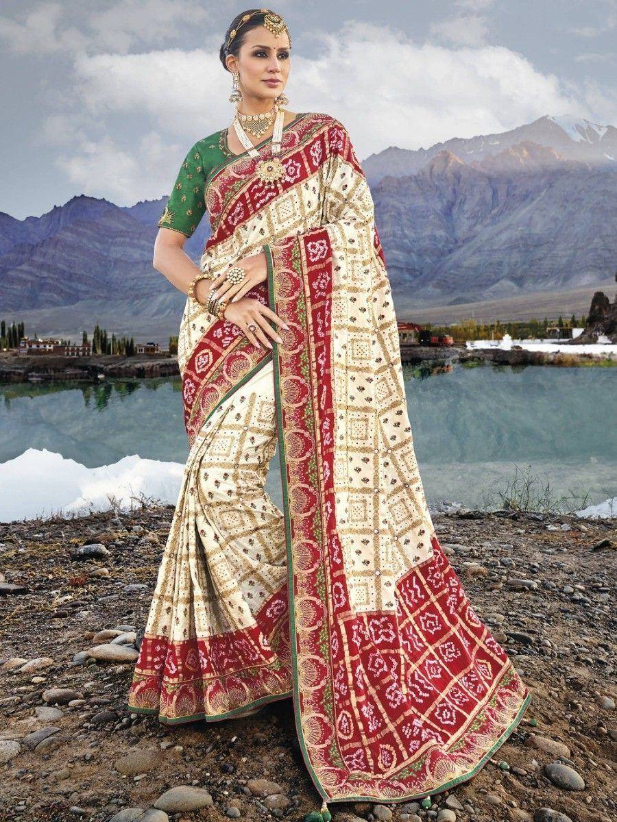 Elegant Indian saree with red, cream, and green geometric print, paired with matching blouse, worn against mountain lake backdrop