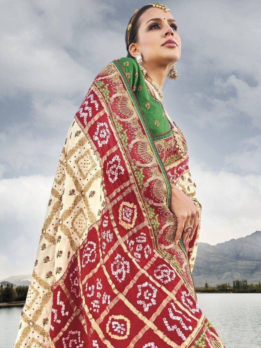 Woman in red and green embroidered Indian saree with gold jewelry, lakeside backdrop