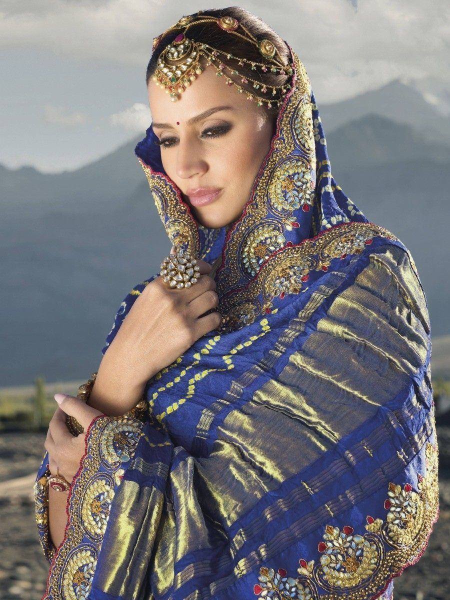 Elegant blue and gold embroidered Indian ethnic wear with traditional jewelry and headpiece