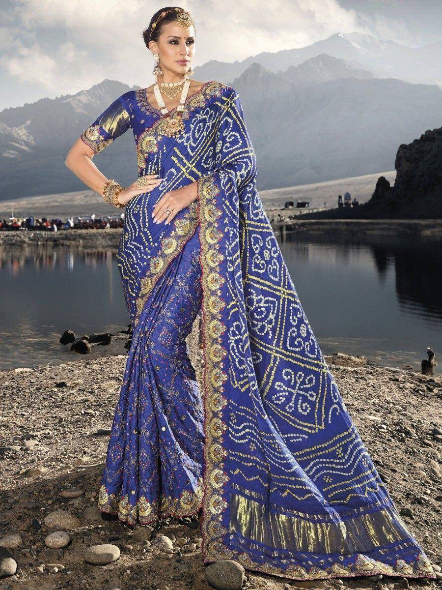 Royal blue embroidered saree with gold patterns, worn by woman near mountain lake, ethnic Indian wear