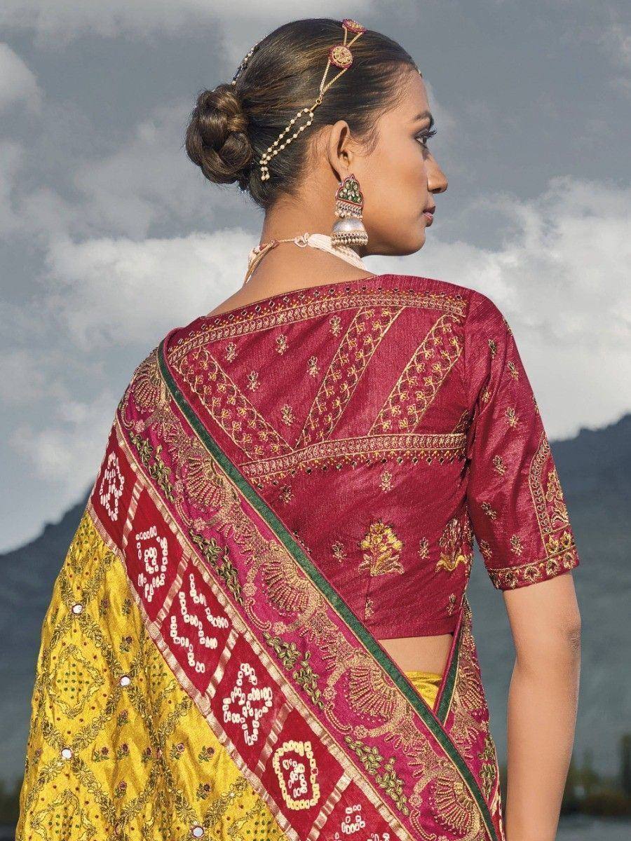 Woman in maroon and yellow embroidered saree with gold detailing, traditional Indian ethnic wear