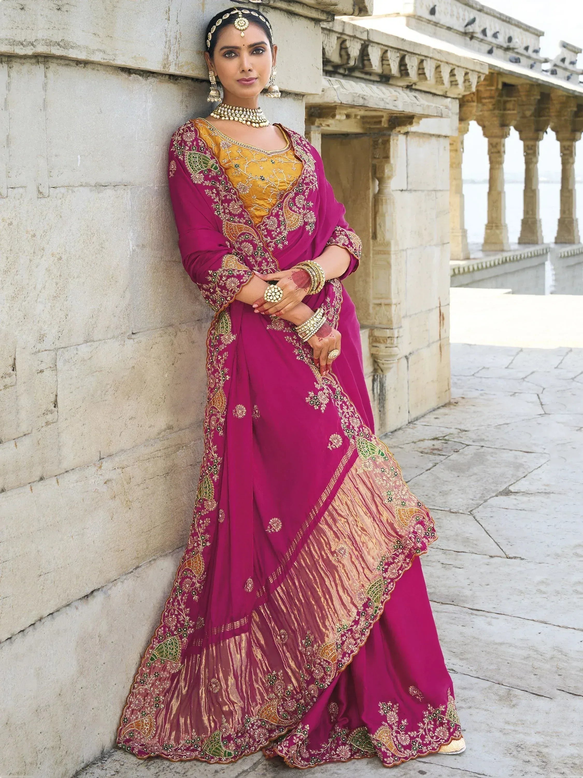 Elegant magenta and gold embroidered Indian ethnic gown with traditional jewelry, perfect for weddings or festive occasions.
