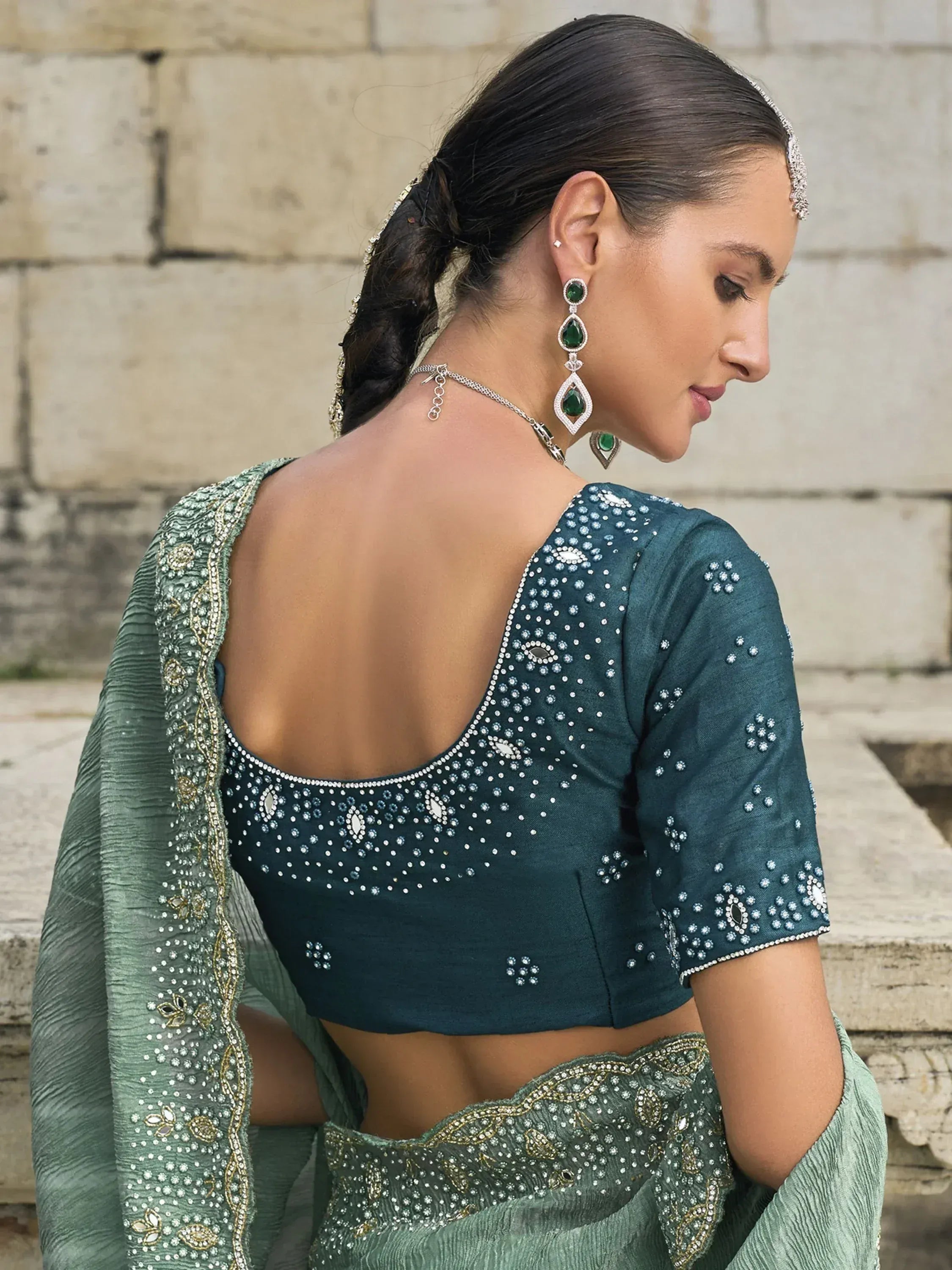 Emerald green designer lehenga choli with backless blouse, intricate embroidery, and statement jewelry