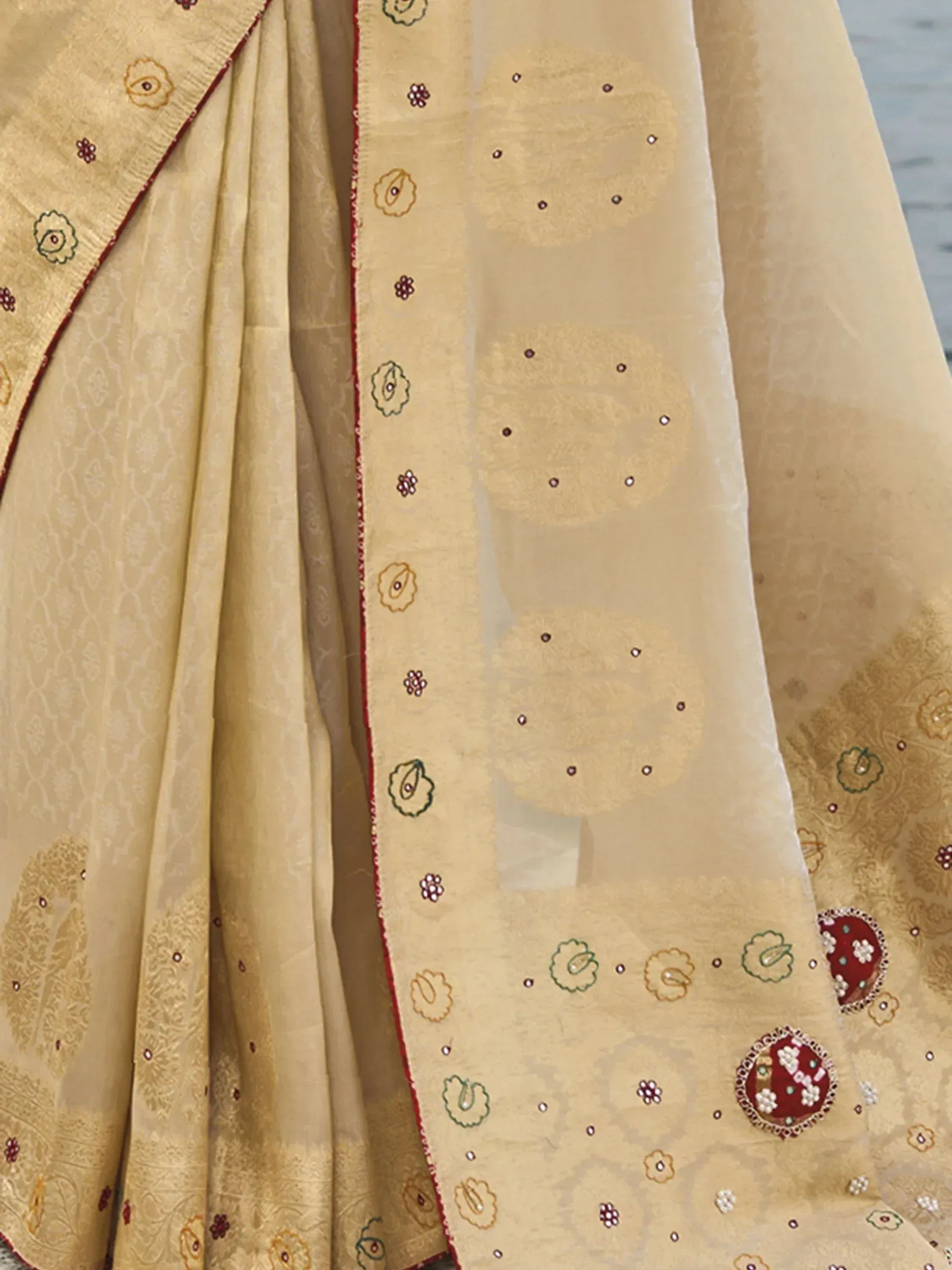 Beige designer saree with floral embroidery, mirror work, and red border for ethnic wear