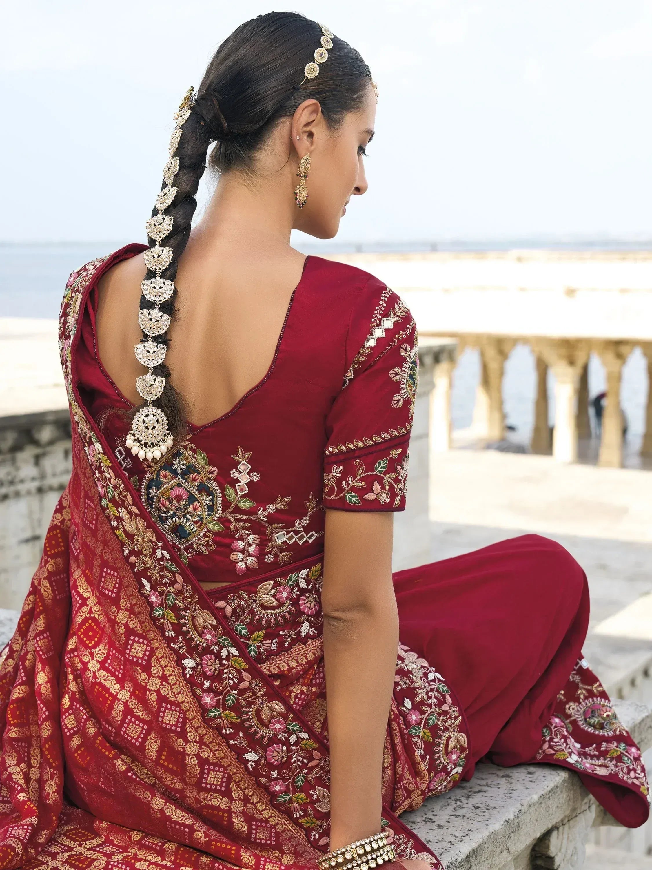 Maroon embroidered saree with floral motifs, backless blouse, and traditional jewelry for ethnic wear