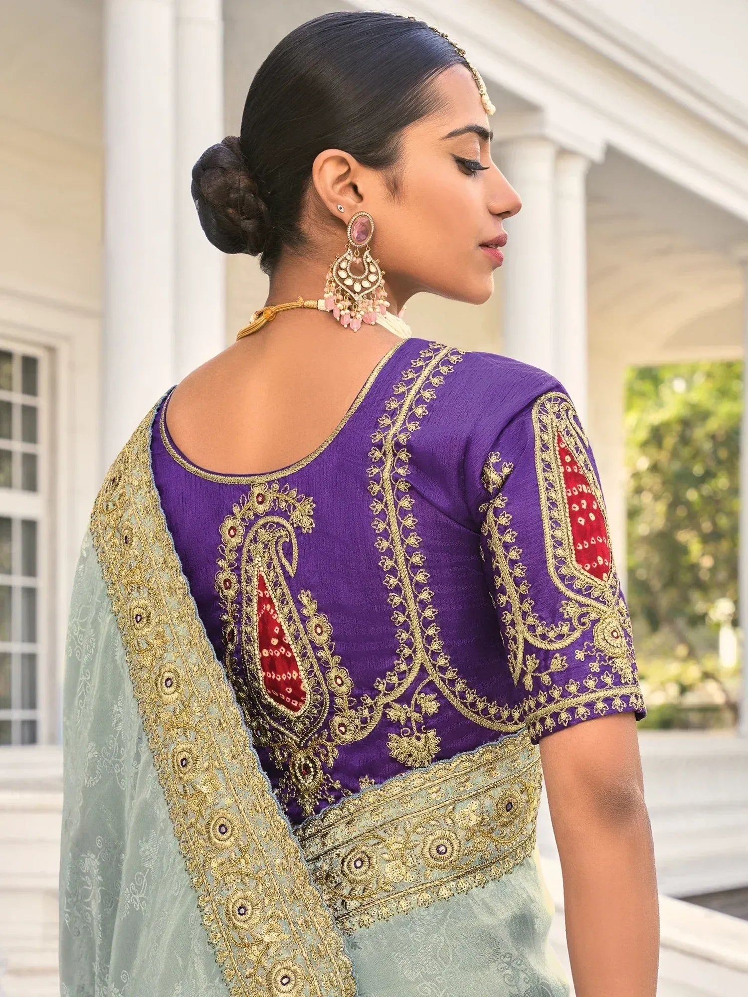 Purple embroidered blouse with gold and red detailing, paired with light green saree, ideal for Indian ethnic wear.