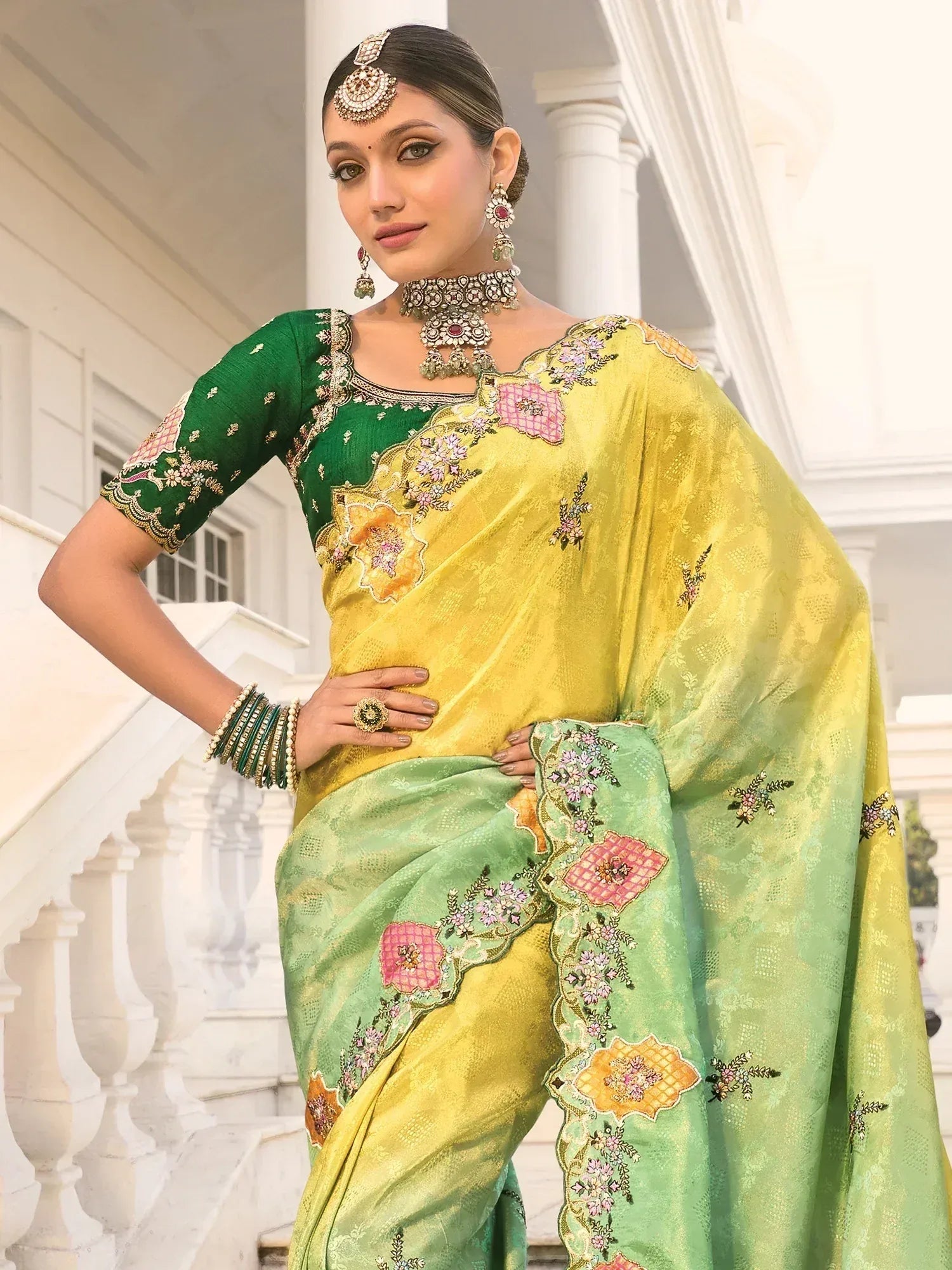 Elegant green and yellow embroidered saree with floral designs and traditional jewelry