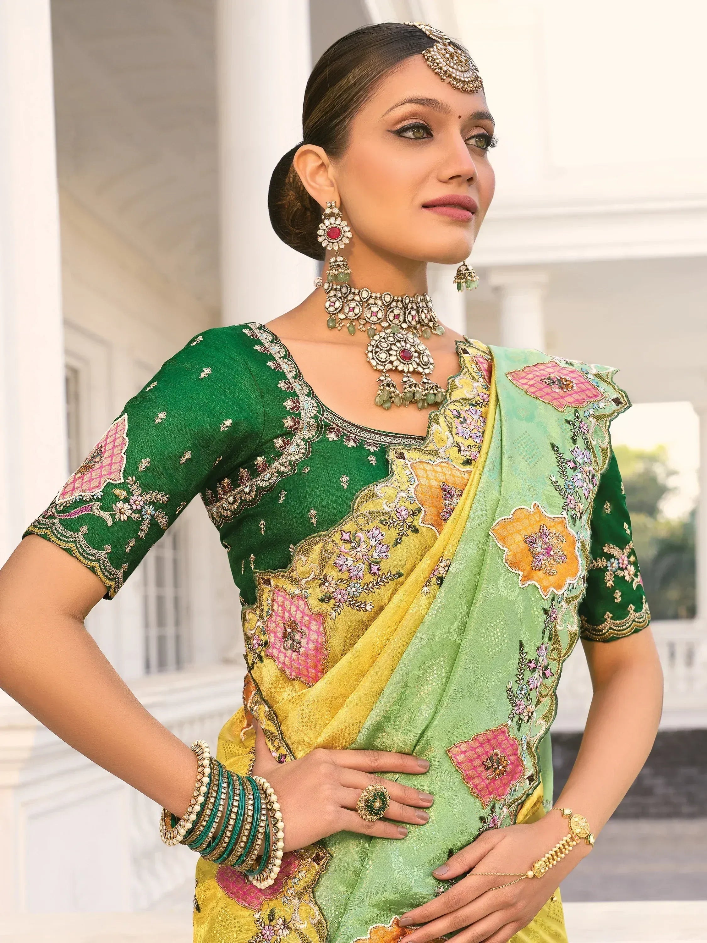 Green and yellow embroidered saree with floral designs and traditional jewelry
