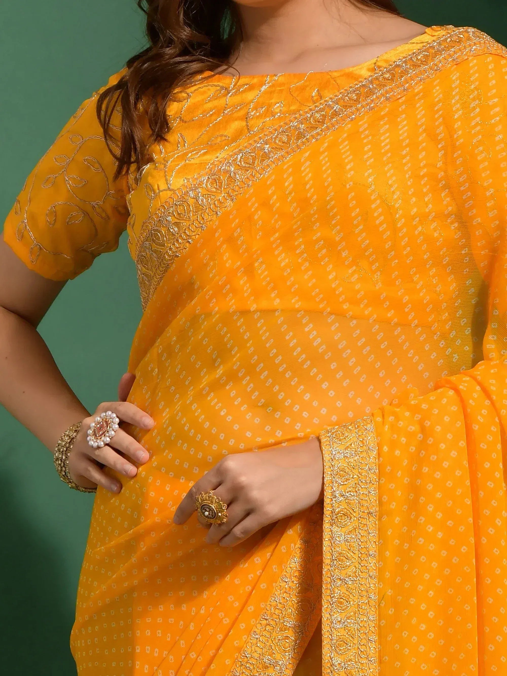 Vibrant yellow saree with gold embroidery and subtle white motifs, paired with matching blouse and traditional jewelry.