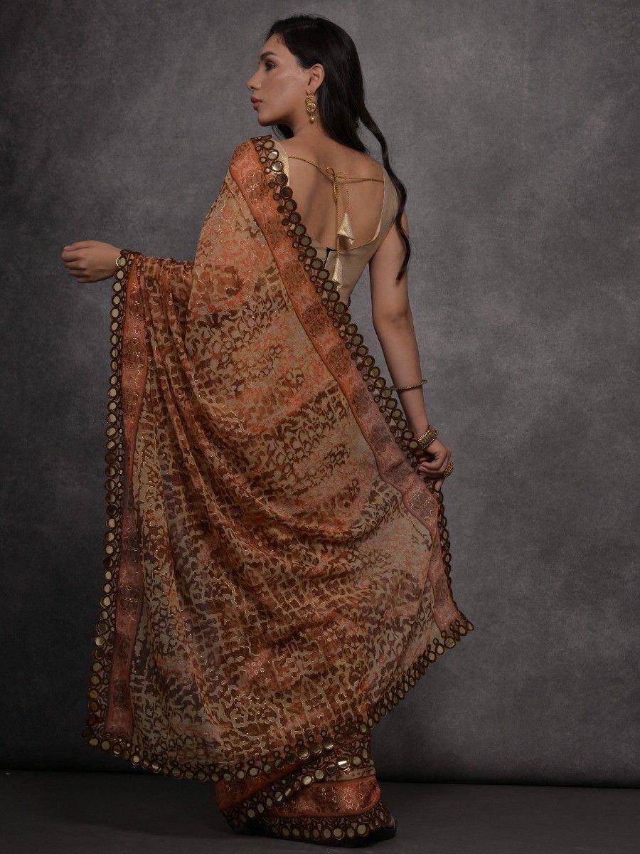 Elegant Indian saree with intricate print and gold coin border, paired with backless blouse for festive occasions
