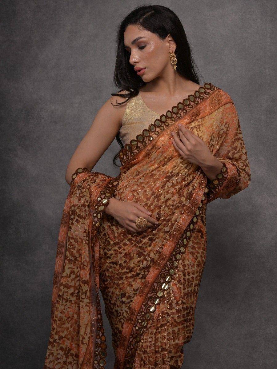 Elegant orange printed saree with mirror work, paired with gold blouse for Indian ethnic wear