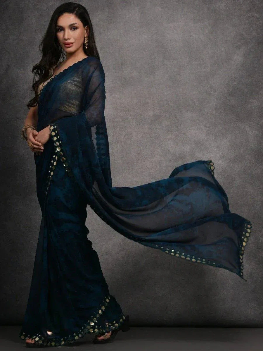 Elegant dark blue saree with gold mirror work, flowing pallu, and sheer blouse for Indian ethnic wear