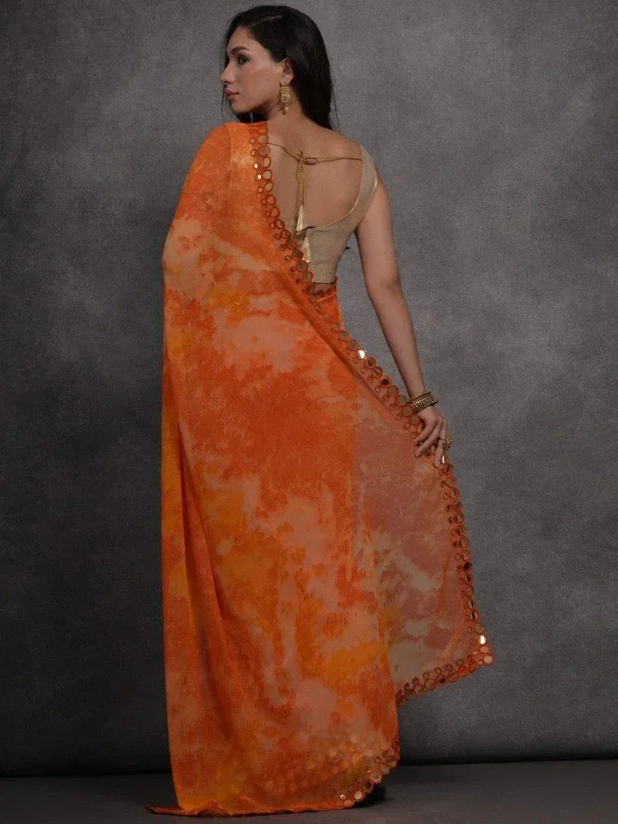 Orange tie-dye saree with mirror work border, paired with gold backless blouse for ethnic wear