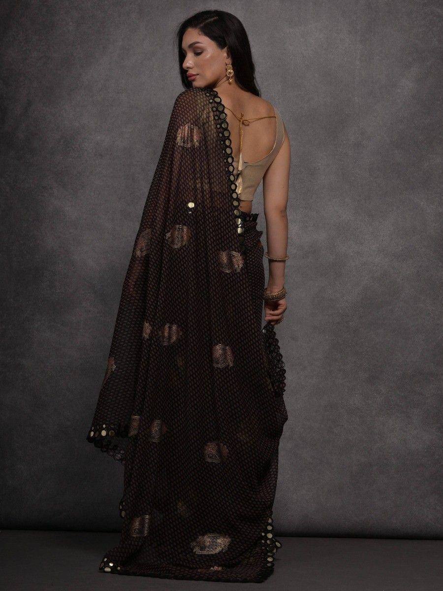 Elegant black saree with gold motifs and scalloped border, paired with a beige blouse for ethnic wear.