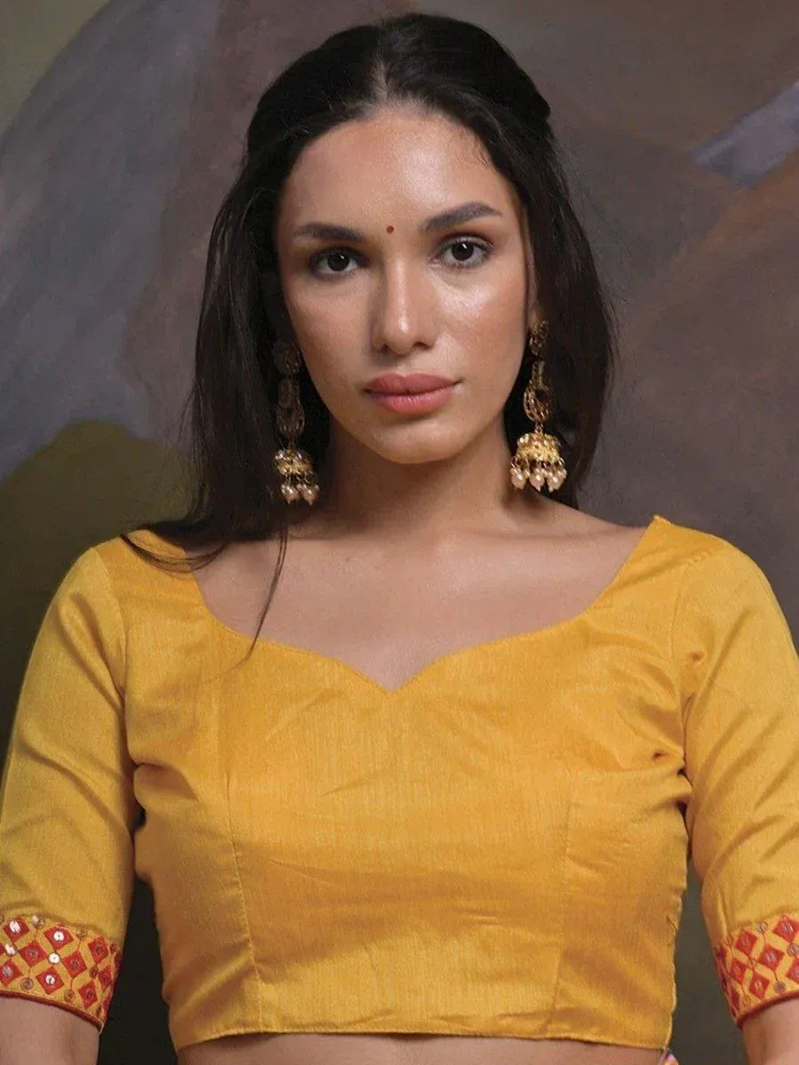 Yellow ethnic blouse with red embroidered sleeves, paired with jhumka earrings for traditional Indian wear