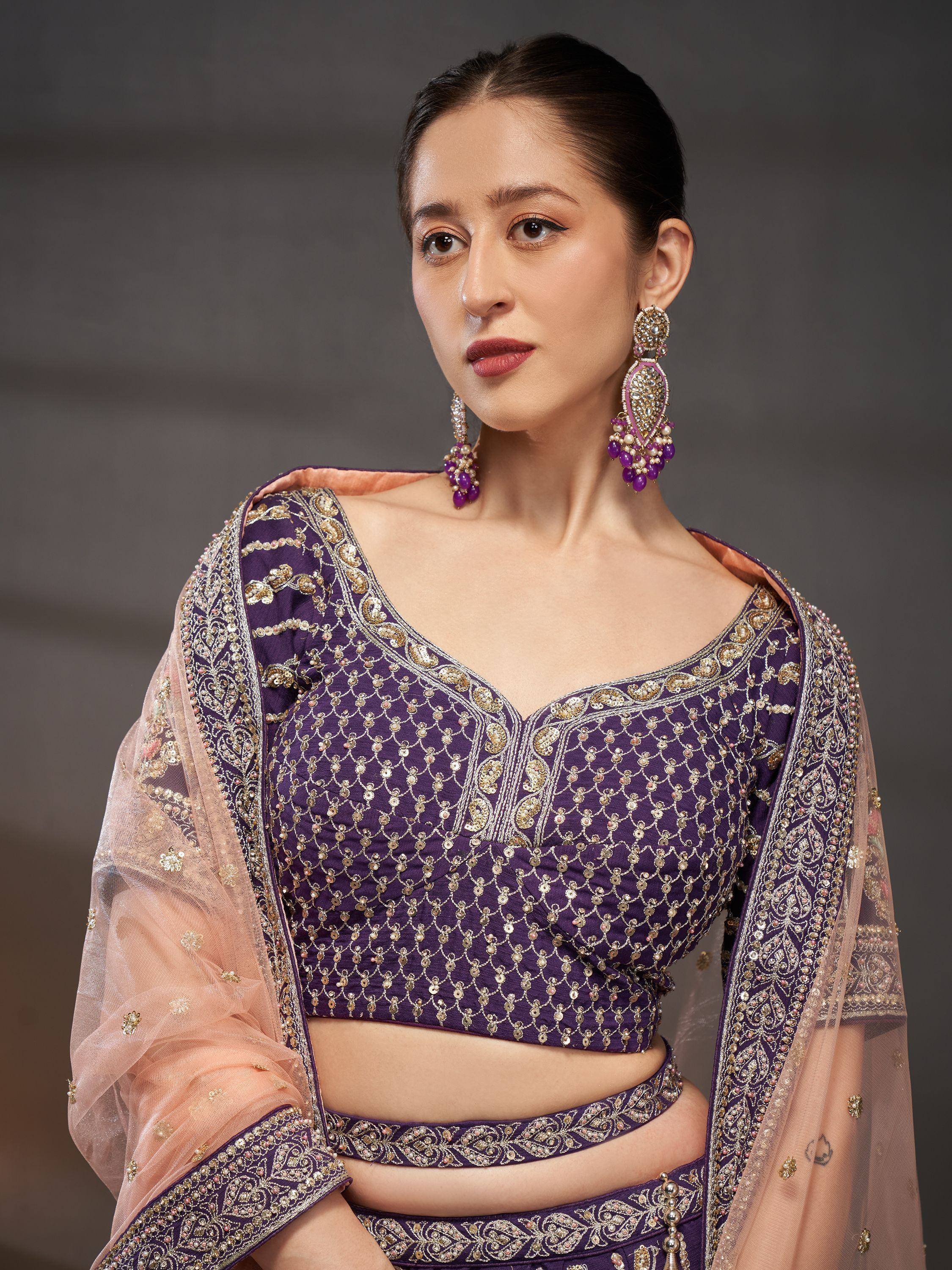 Purple embroidered lehenga choli with gold detailing and sheer dupatta, paired with statement earrings.