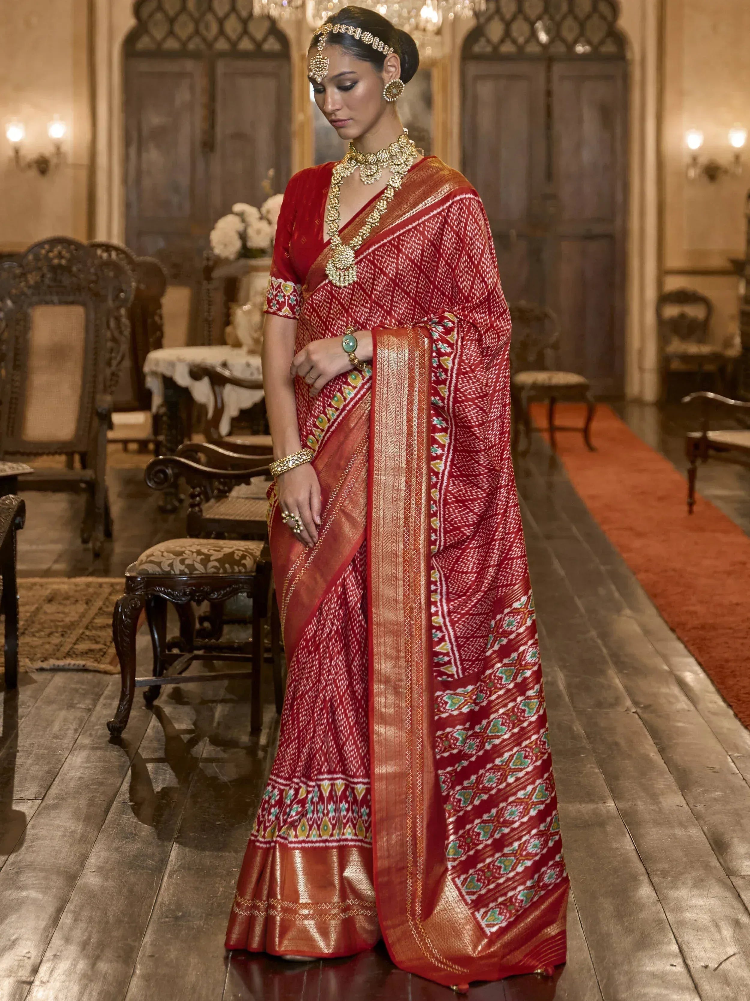 Red ethnic saree with gold border and traditional jewelry, perfect for Indian weddings and festive occasions.