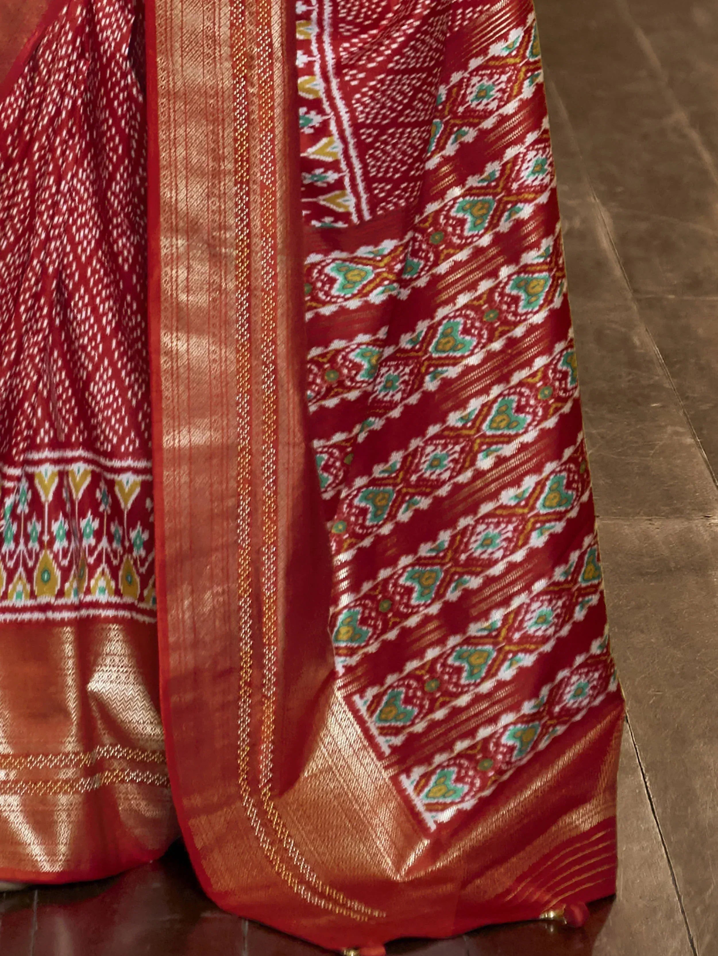 Red and gold ethnic saree with intricate ikat patterns and woven border details