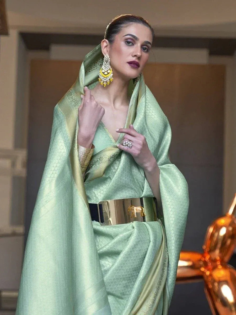 Mint green designer saree with gold border, elephant belt, and statement earrings for ethnic wear