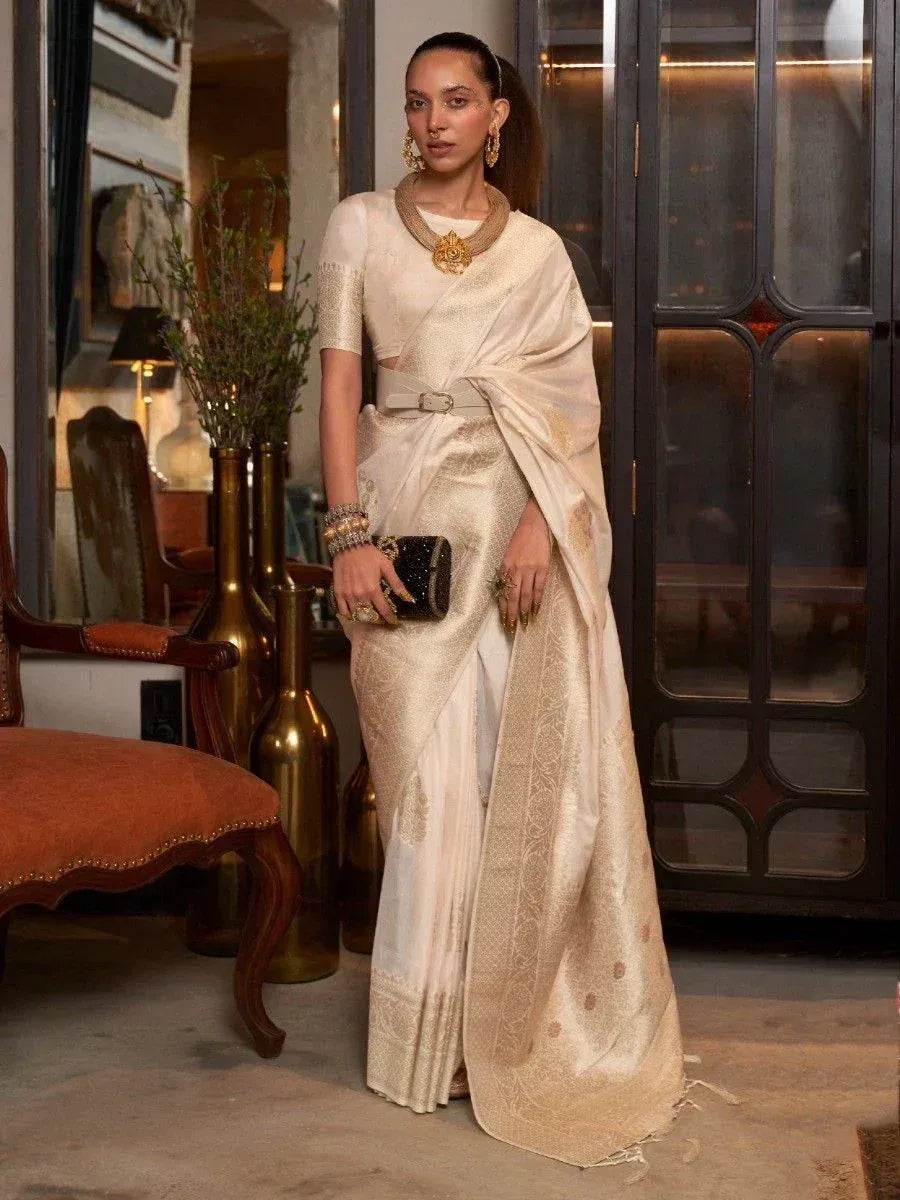 Elegant cream saree with gold embroidery, paired with statement jewelry and a belt, styled for ethnic occasions.