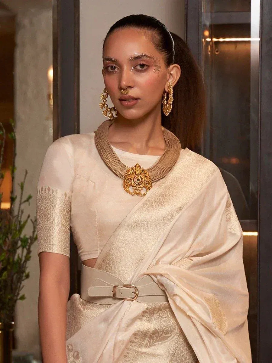 Elegant cream saree with gold embroidery, statement necklace, and modern belt for Indian ethnic wear