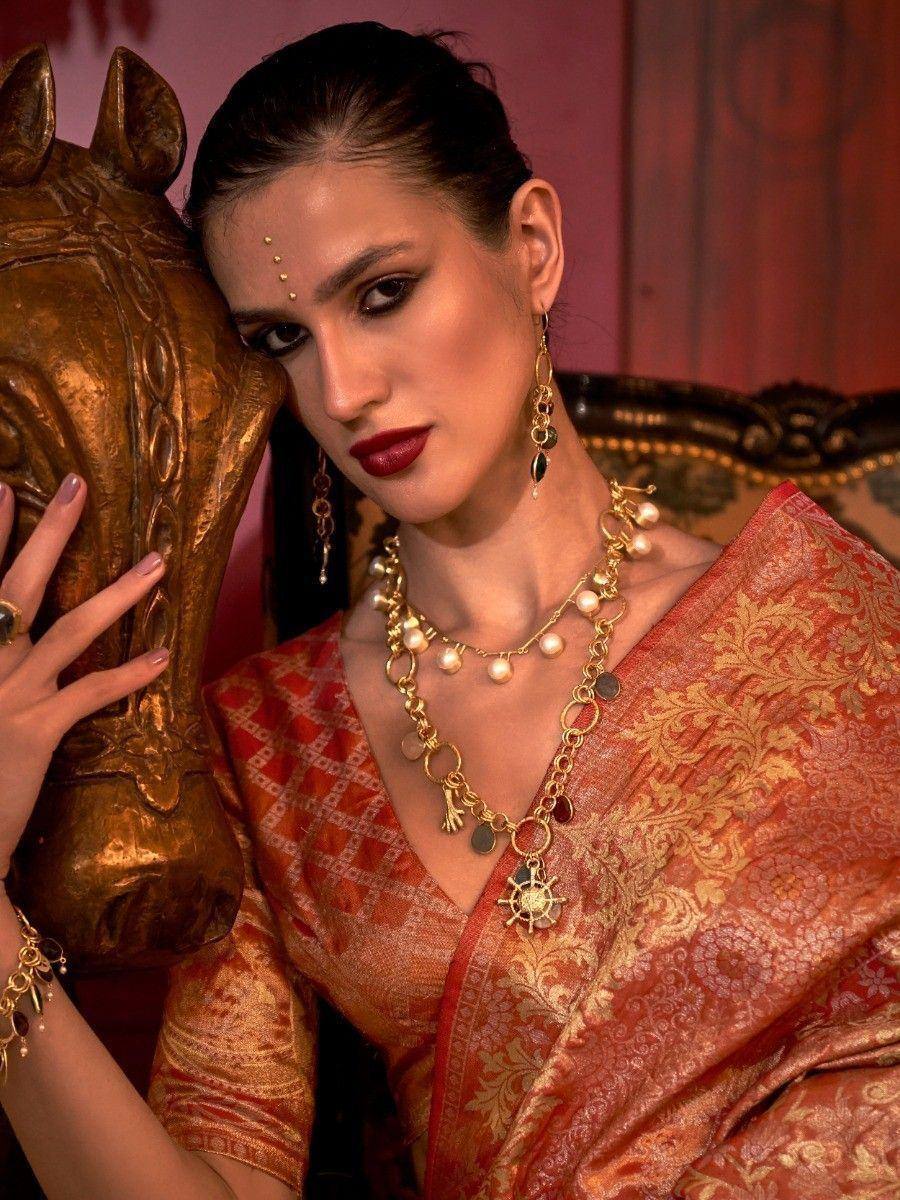 Woman in red and gold ethnic saree with pearl and gold jewelry, traditional Indian attire