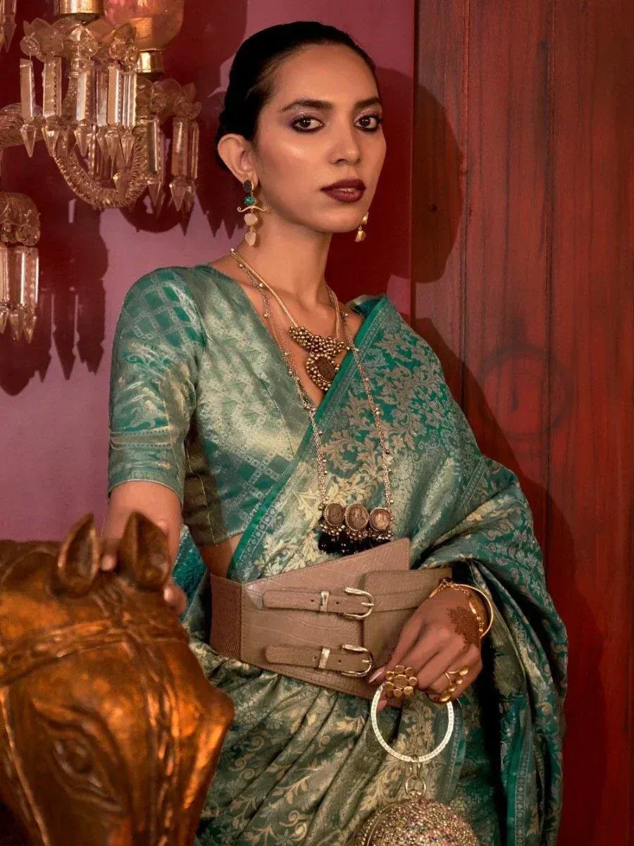Woman in elegant green designer saree with gold jewelry and wide belt, perfect for ethnic occasions.