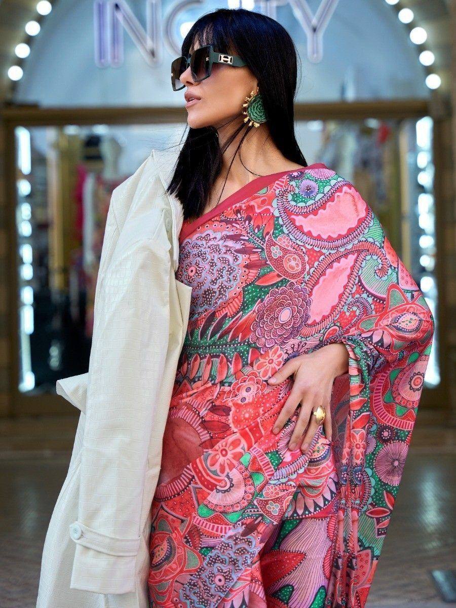 Woman in vibrant printed ethnic gown with floral paisley design, styled with white coat and sunglasses