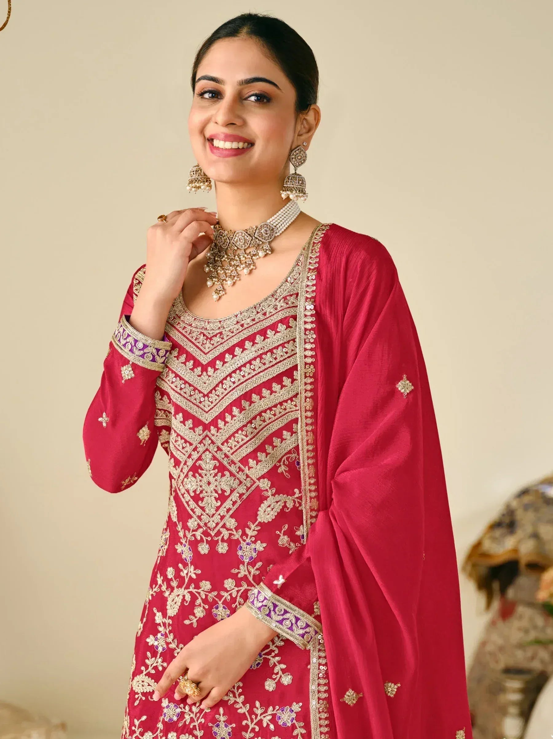 Woman in red embroidered Indian ethnic wear with gold and purple detailing, paired with traditional jewelry
