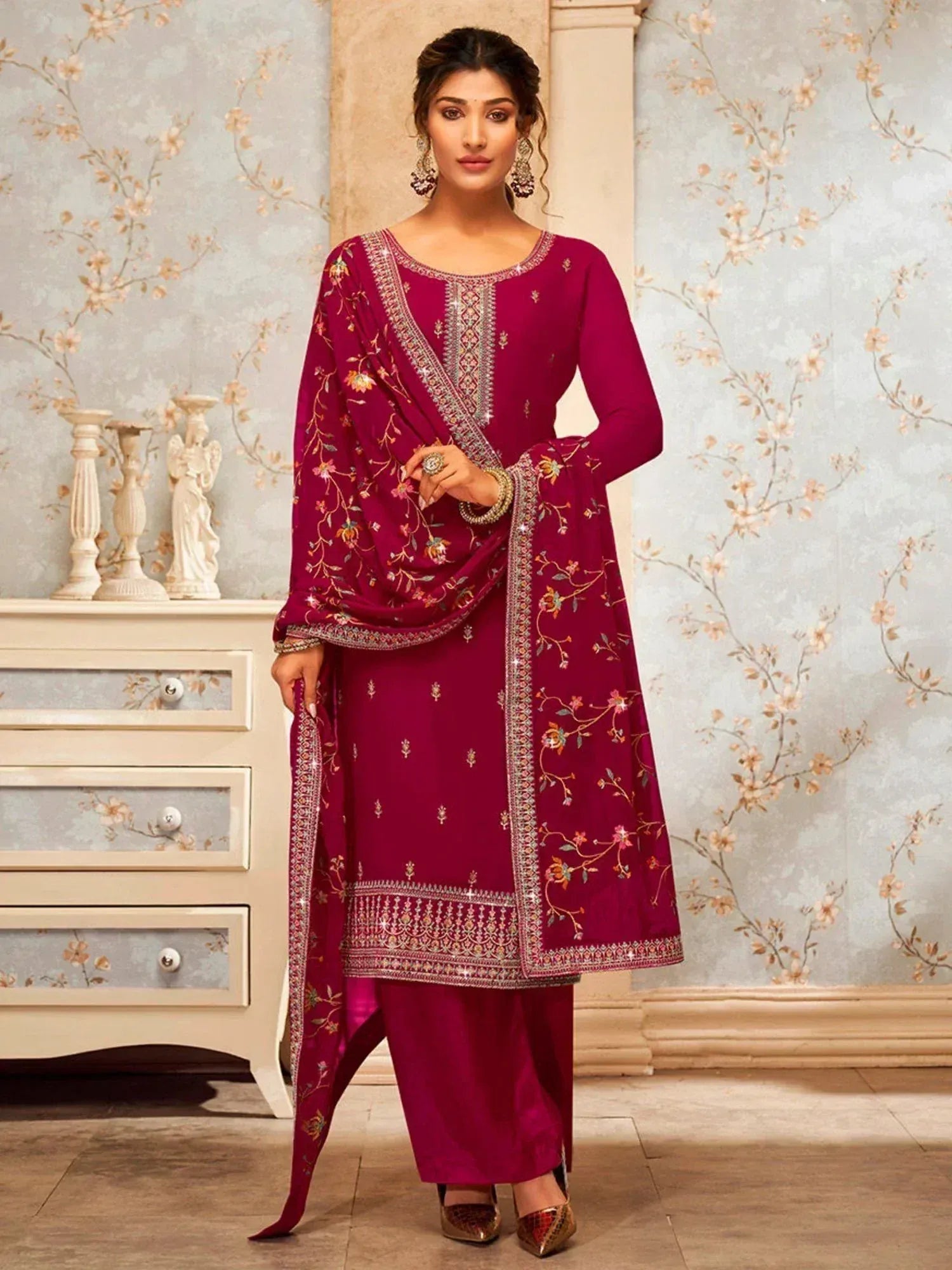 Woman wearing maroon embroidered salwar kameez with dupatta, standing indoors