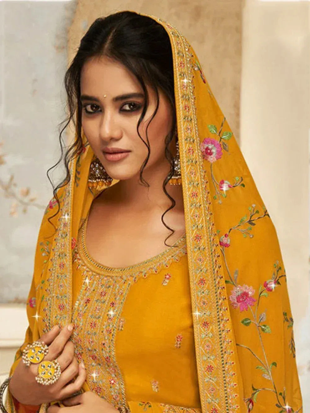 Woman in yellow embroidered salwar kameez with floral dupatta, traditional Indian attire
