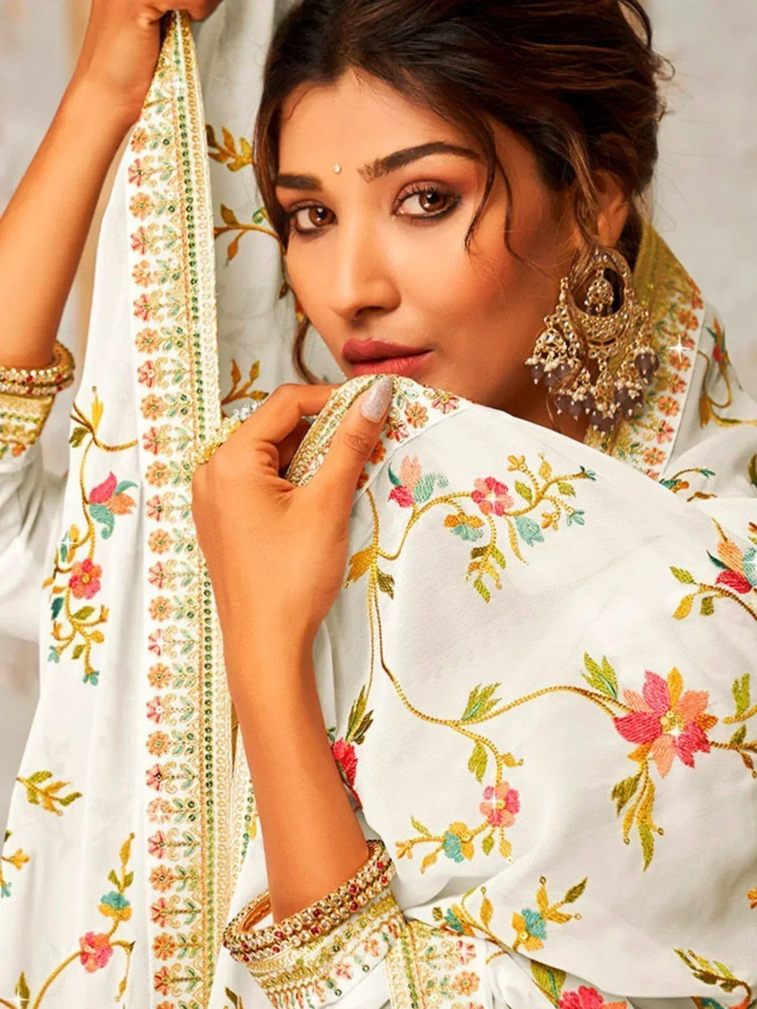 Woman in white floral embroidered dupatta and ethnic jewelry, traditional Indian attire