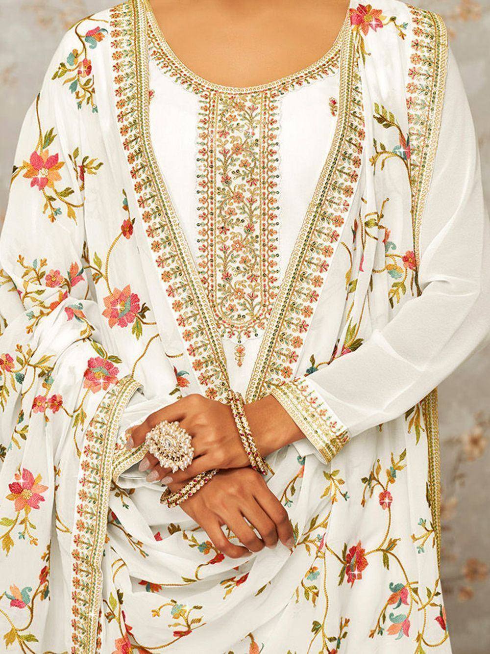 White embroidered salwar kameez with floral patterns and gold jewelry accents
