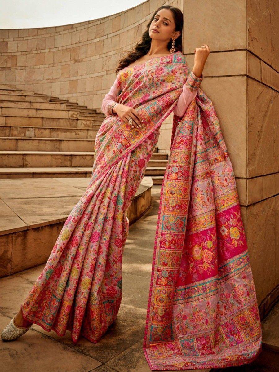 Woman in vibrant pink floral saree with intricate border, styled for ethnic occasions