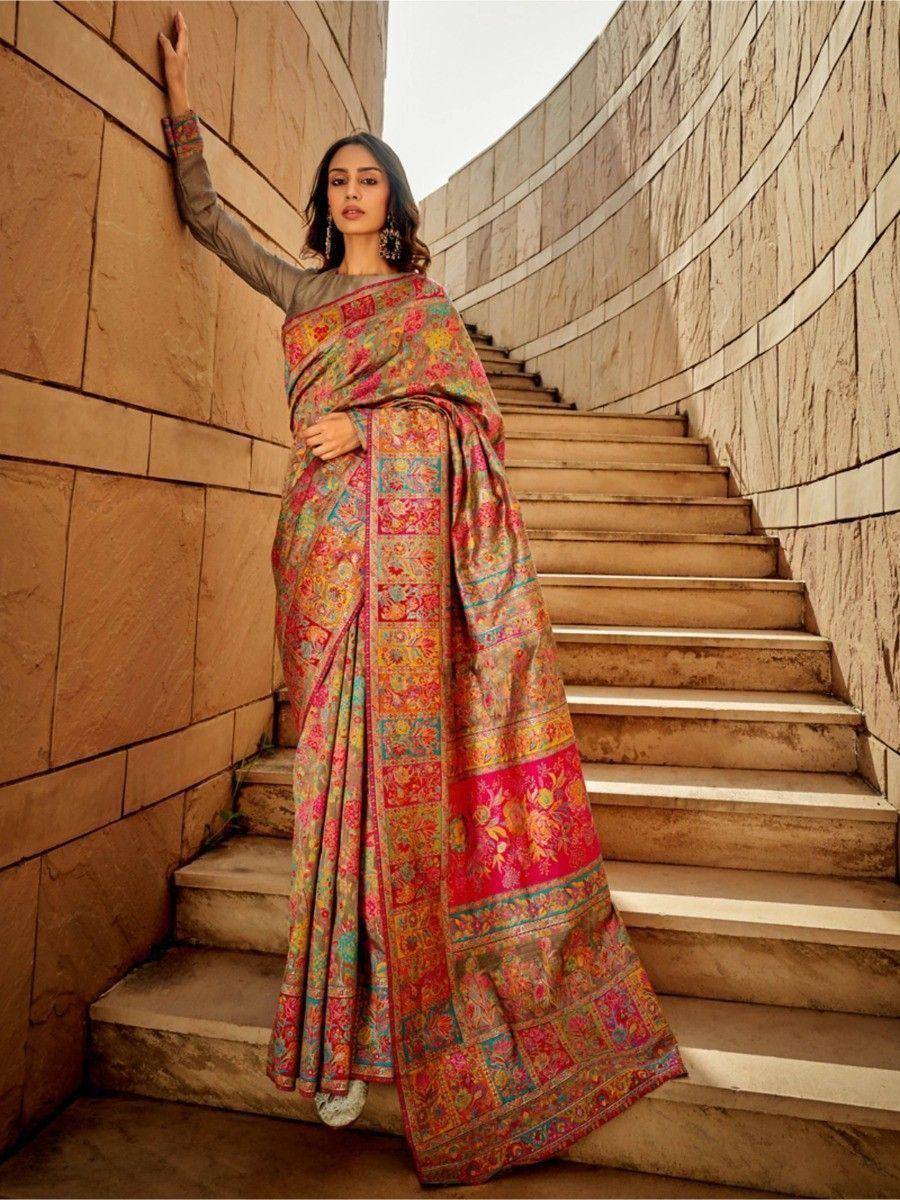 Woman in colorful printed saree with floral motifs, standing on stone stairs, ethnic wear fashion