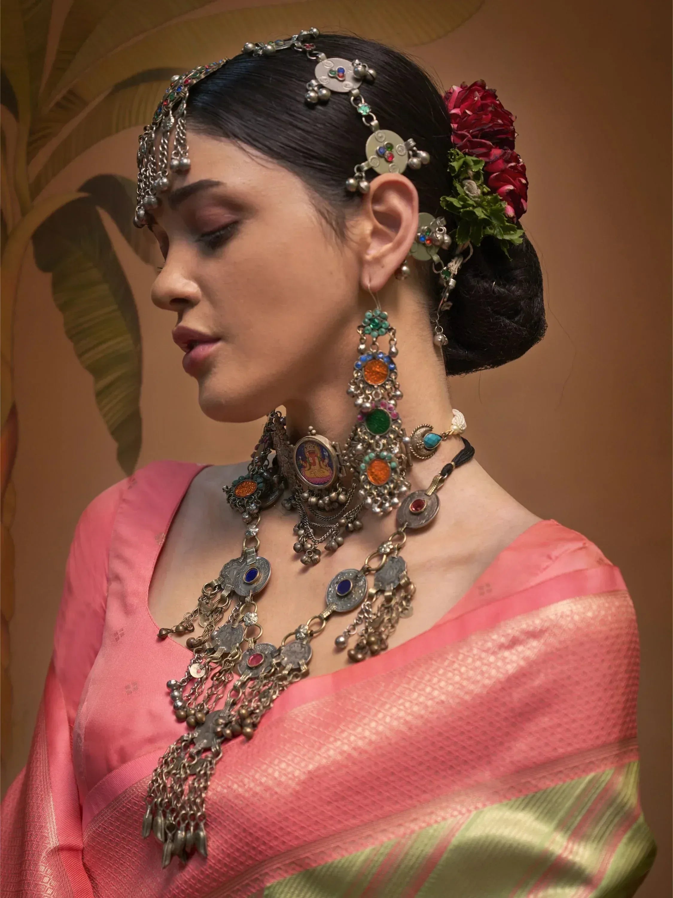 Elegant woman in pink saree with intricate ethnic jewelry and floral hair accessory