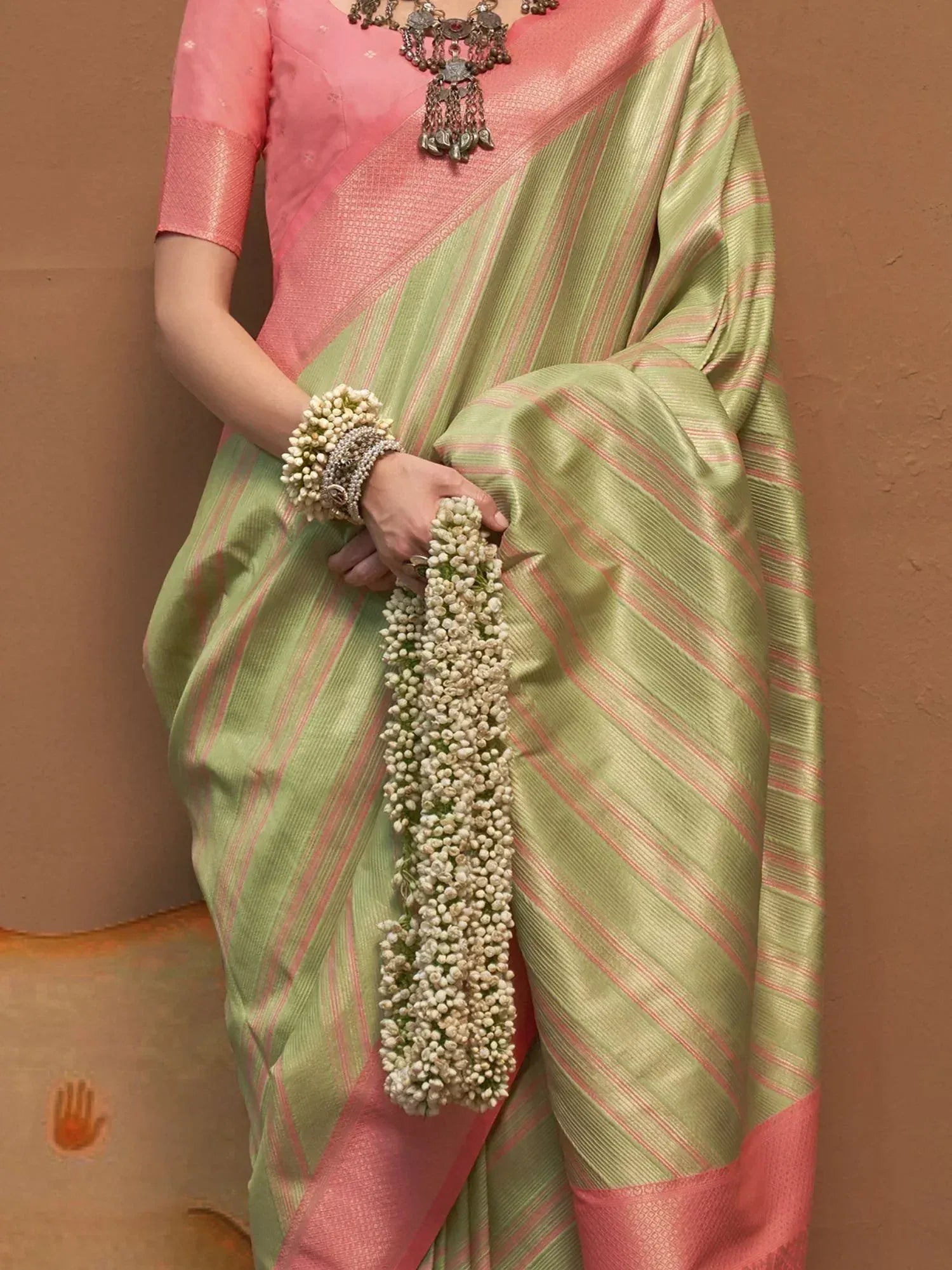 Woman in green and pink striped saree with floral garland, traditional Indian ethnic wear