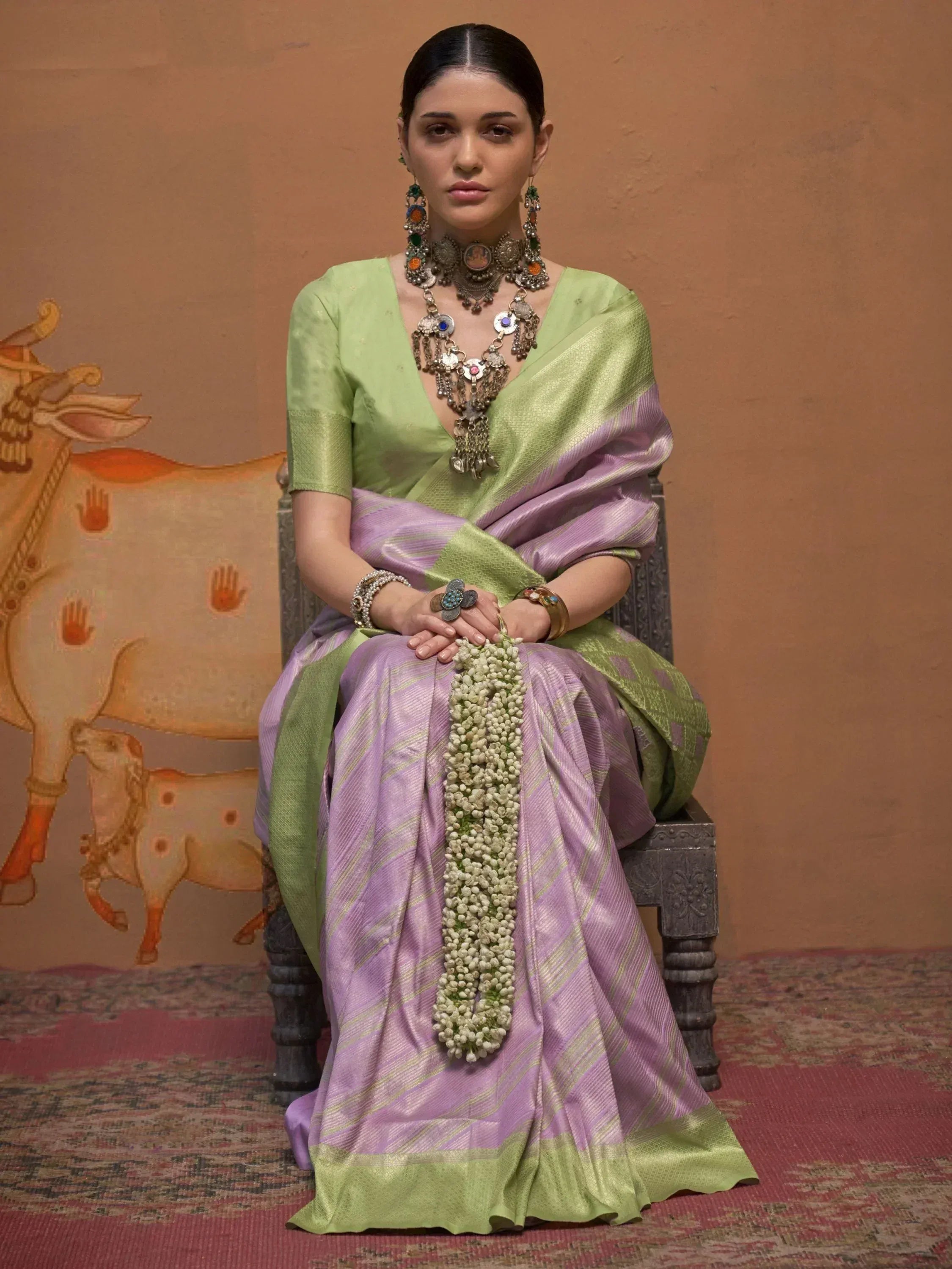 Woman in green and purple silk saree with traditional jewelry and floral garland, Indian ethnic wear