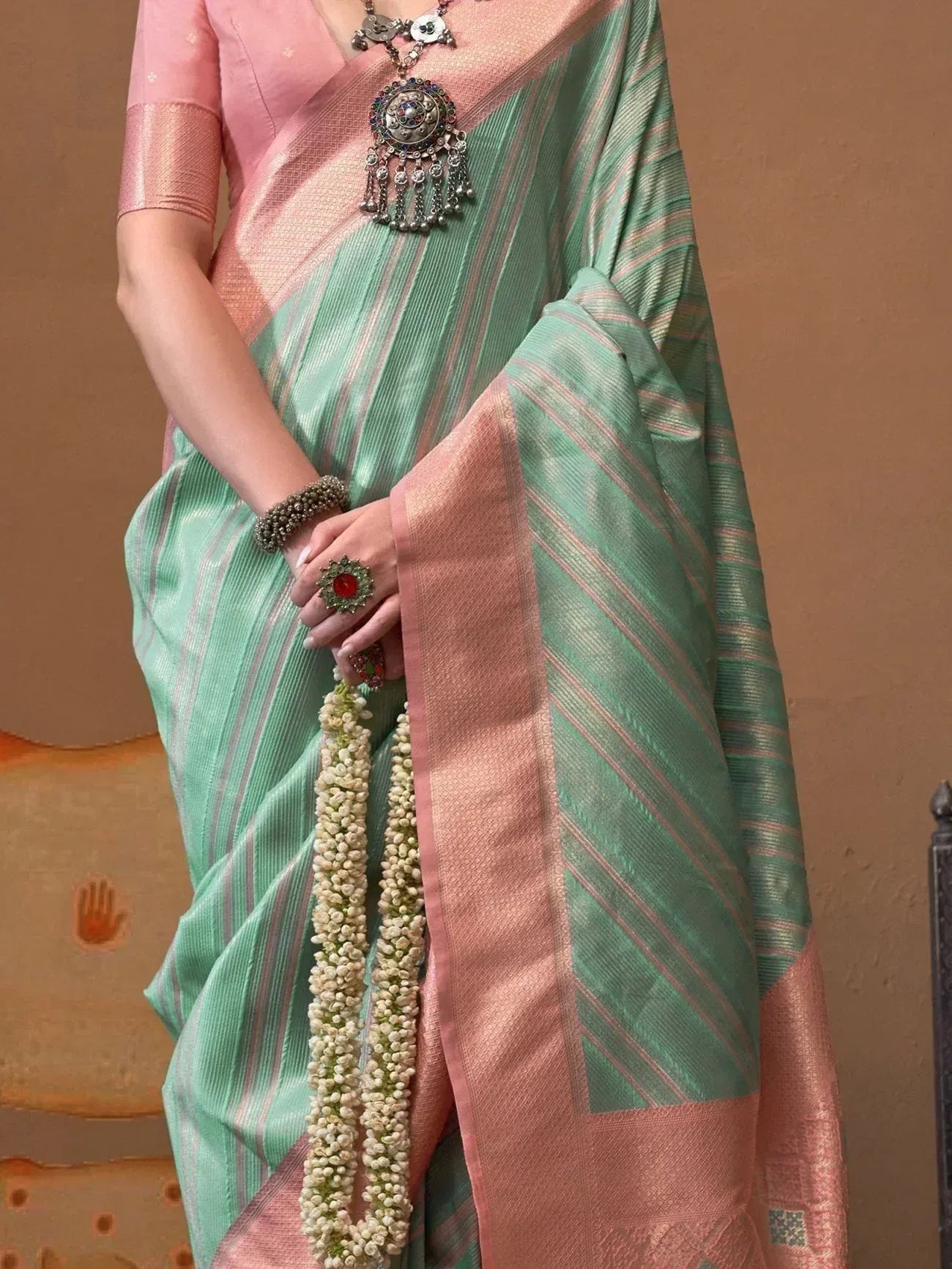 Mint green and pink striped saree with blouse, traditional jewelry, and floral garland for ethnic wear