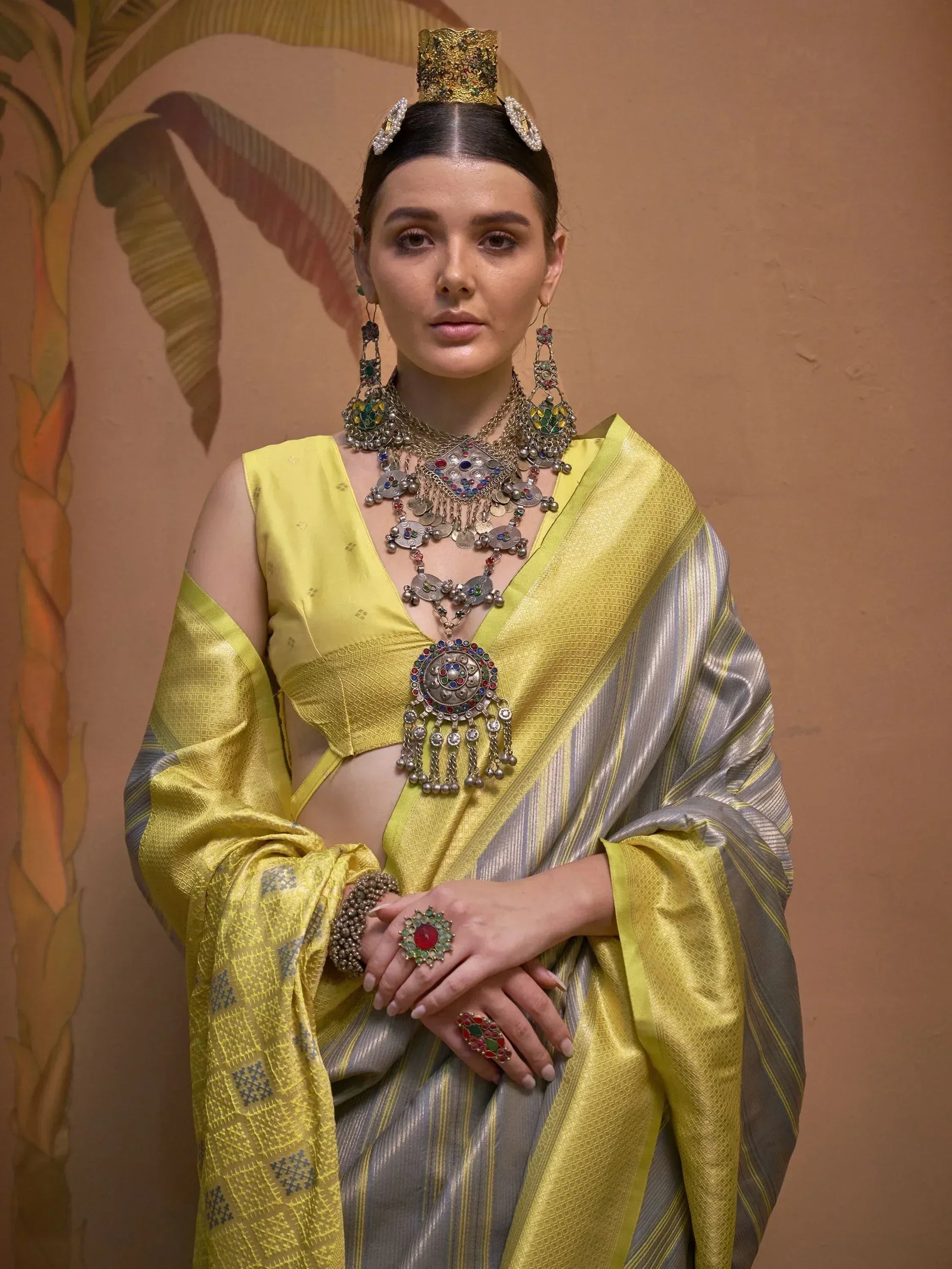 Woman in yellow and silver ethnic saree with traditional jewelry and headpiece