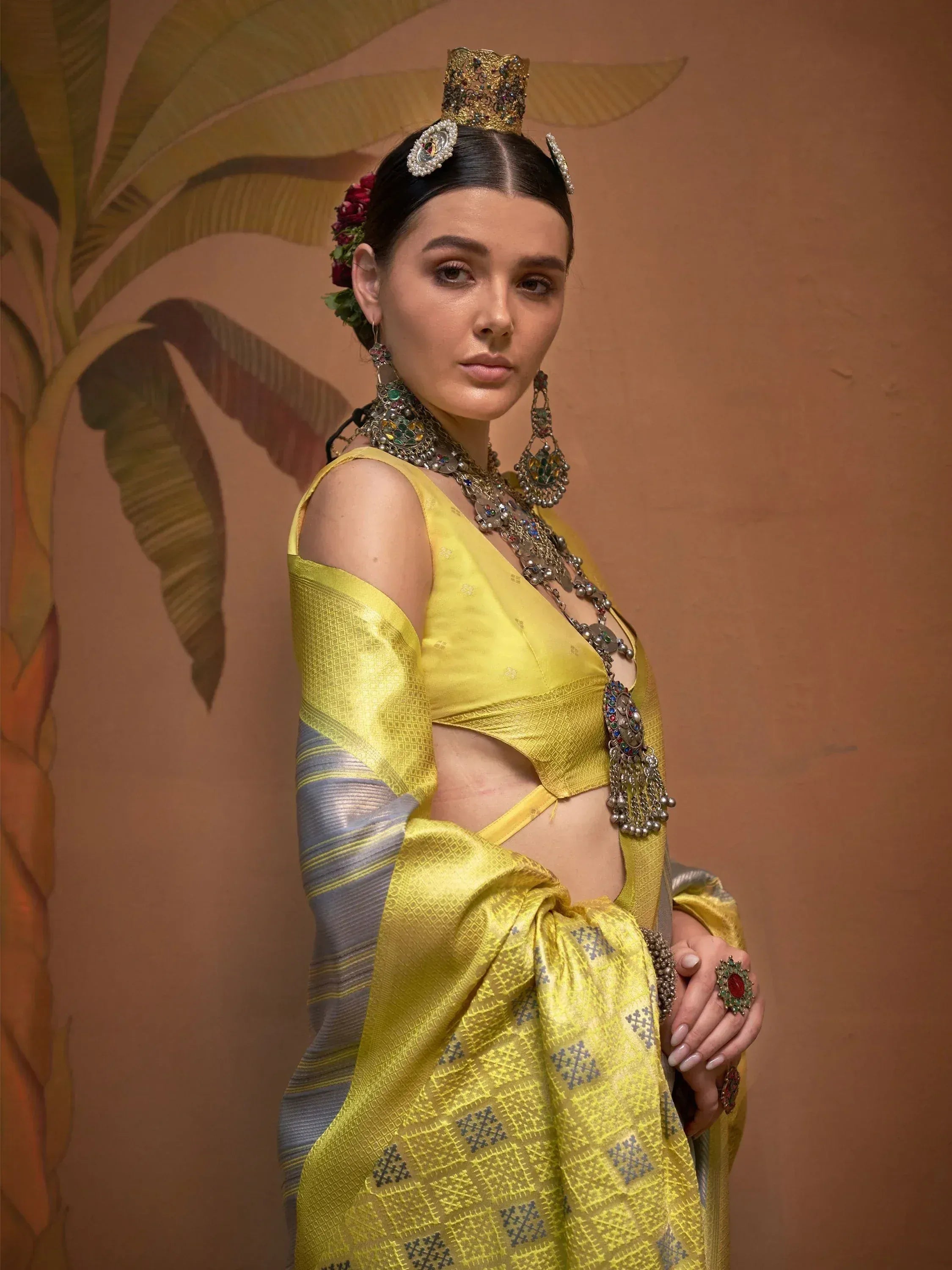Yellow designer saree with blue patterns, statement jewelry, and traditional headpiece for ethnic wear