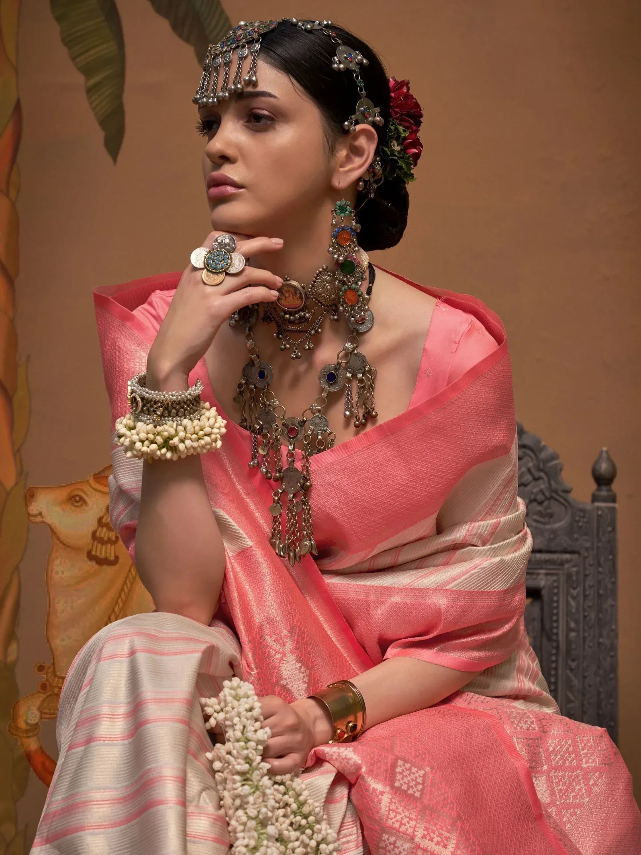 Woman in pink ethnic saree with traditional jewelry and floral accessories, perfect for Indian occasions