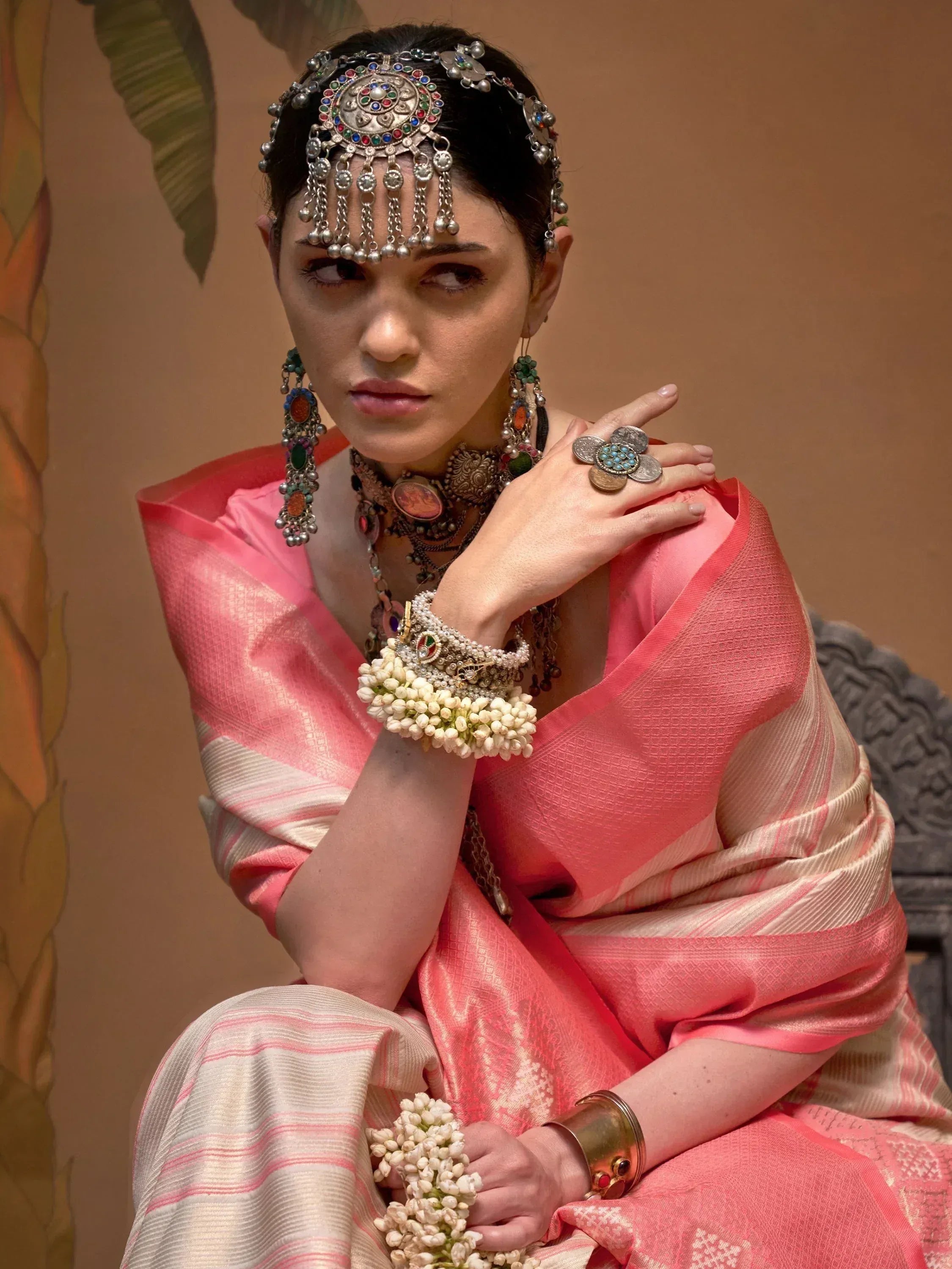 Woman in pink ethnic saree with traditional Indian jewelry and floral accessories