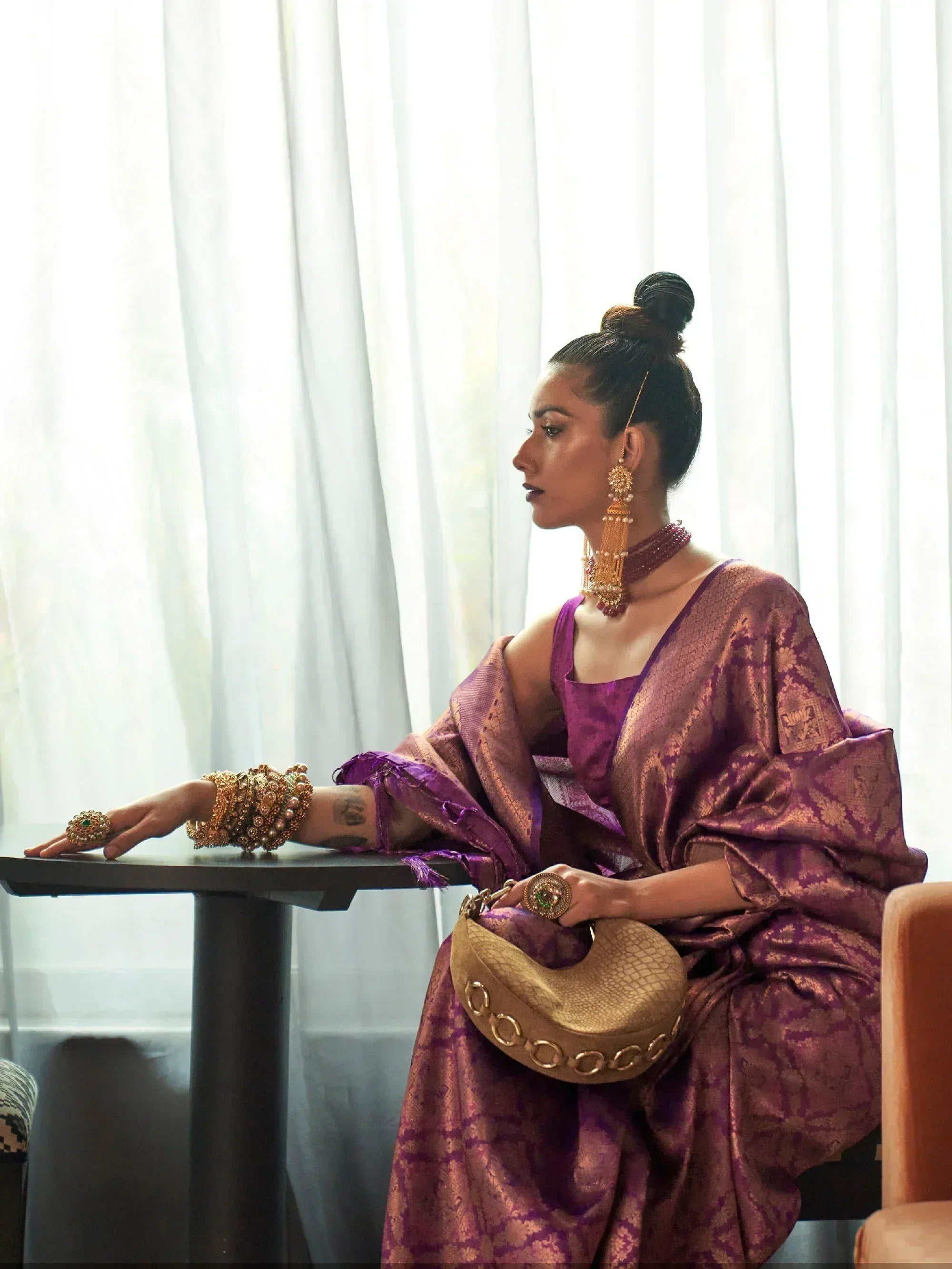 Woman in purple ethnic gown with gold jewelry, styled for Indian occasions