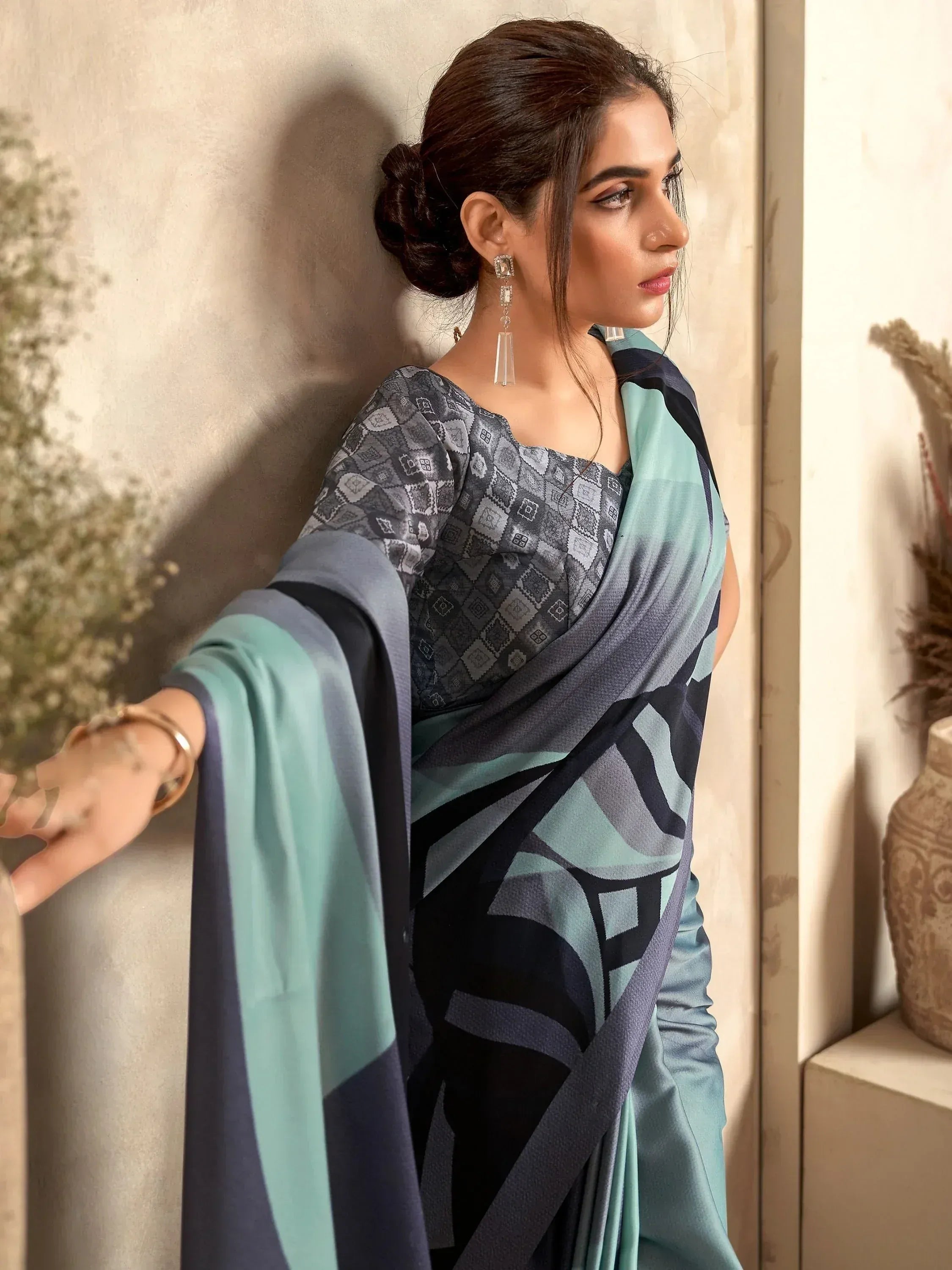Woman in elegant blue and grey printed saree with geometric pattern, styled with statement earrings.